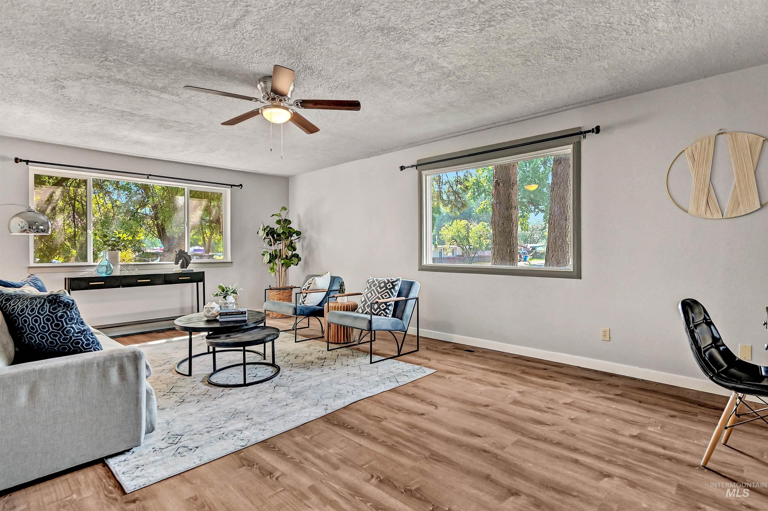 Living area with wood finished floors, a textured ceiling, a ceiling fan, and baseboard heating