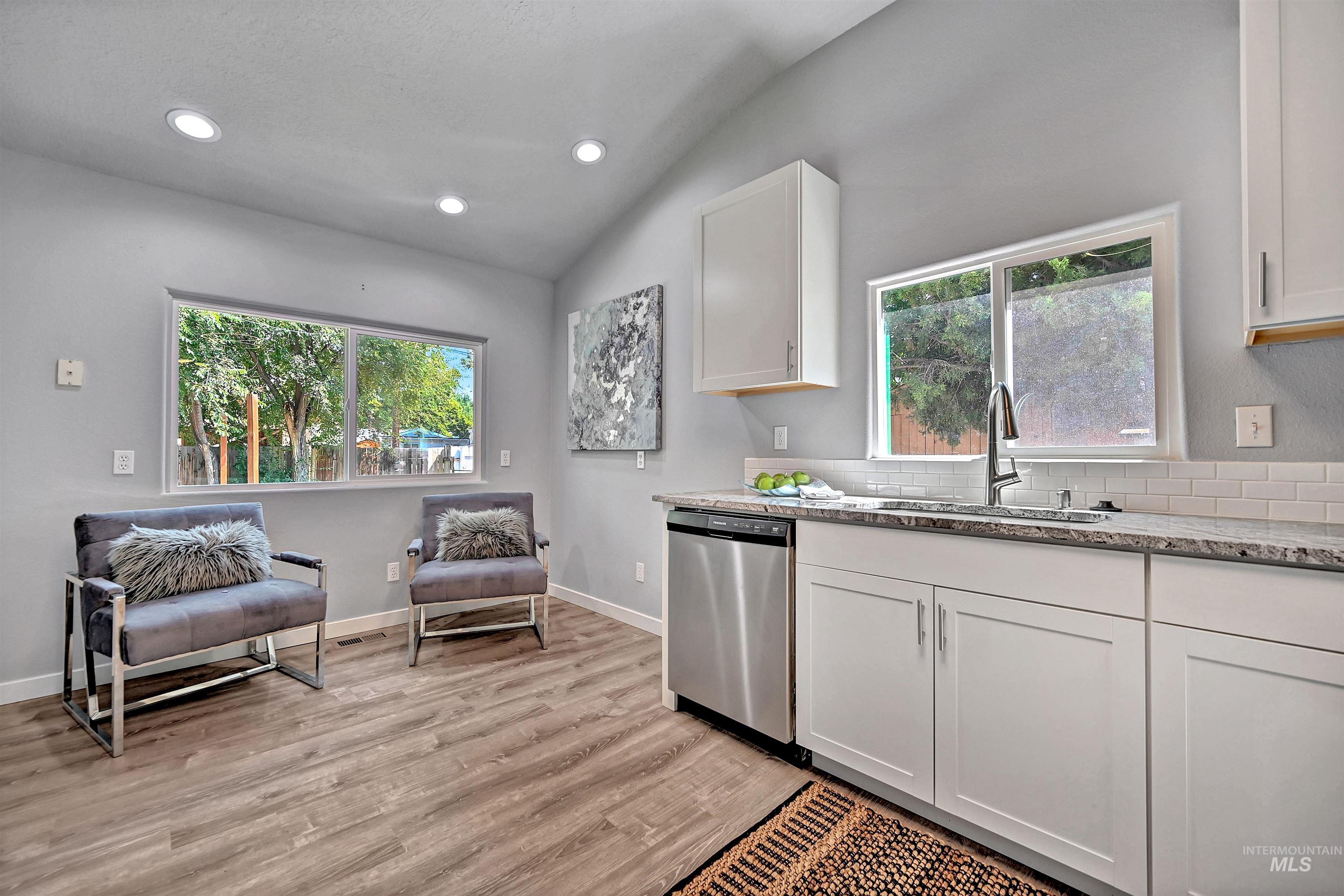 Kitchen with light stone countertops, recessed lighting, healthy amount of natural light, white cabinets, and stainless steel dishwasher