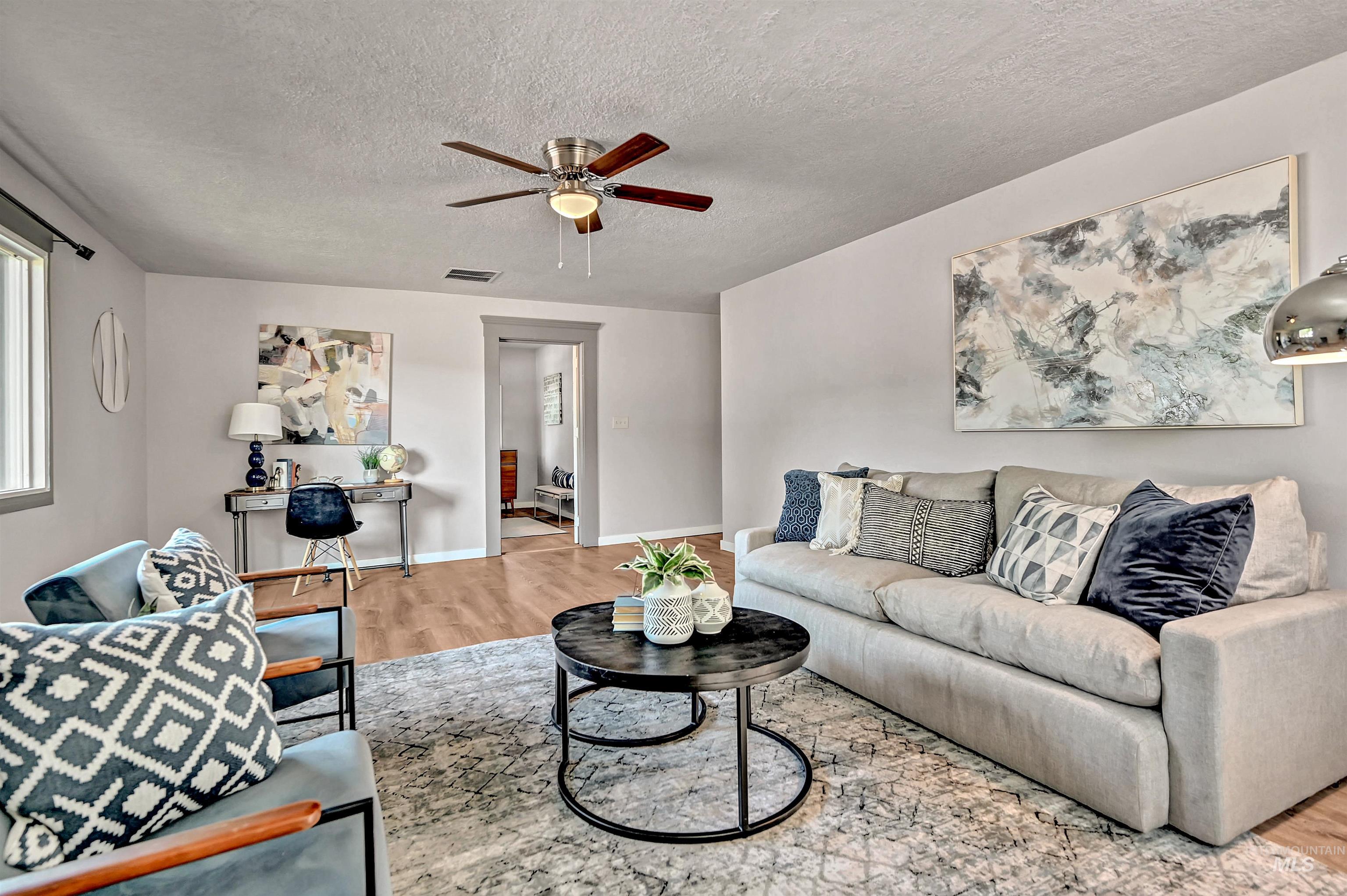 Living room featuring wood finished floors, a textured ceiling, and ceiling fan
