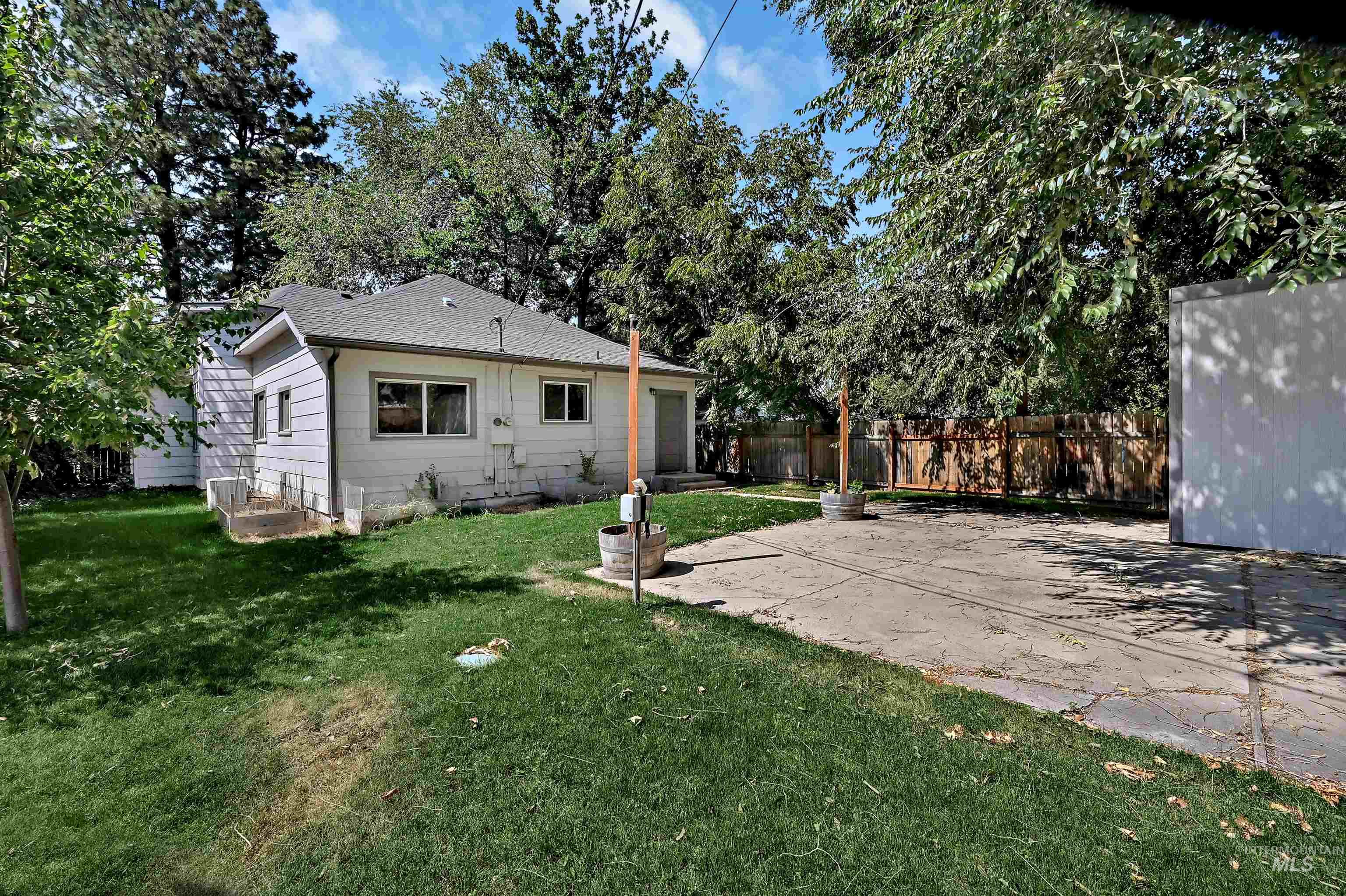 Rear view of property with a fenced backyard, a patio, a shingled roof, and an attached garage