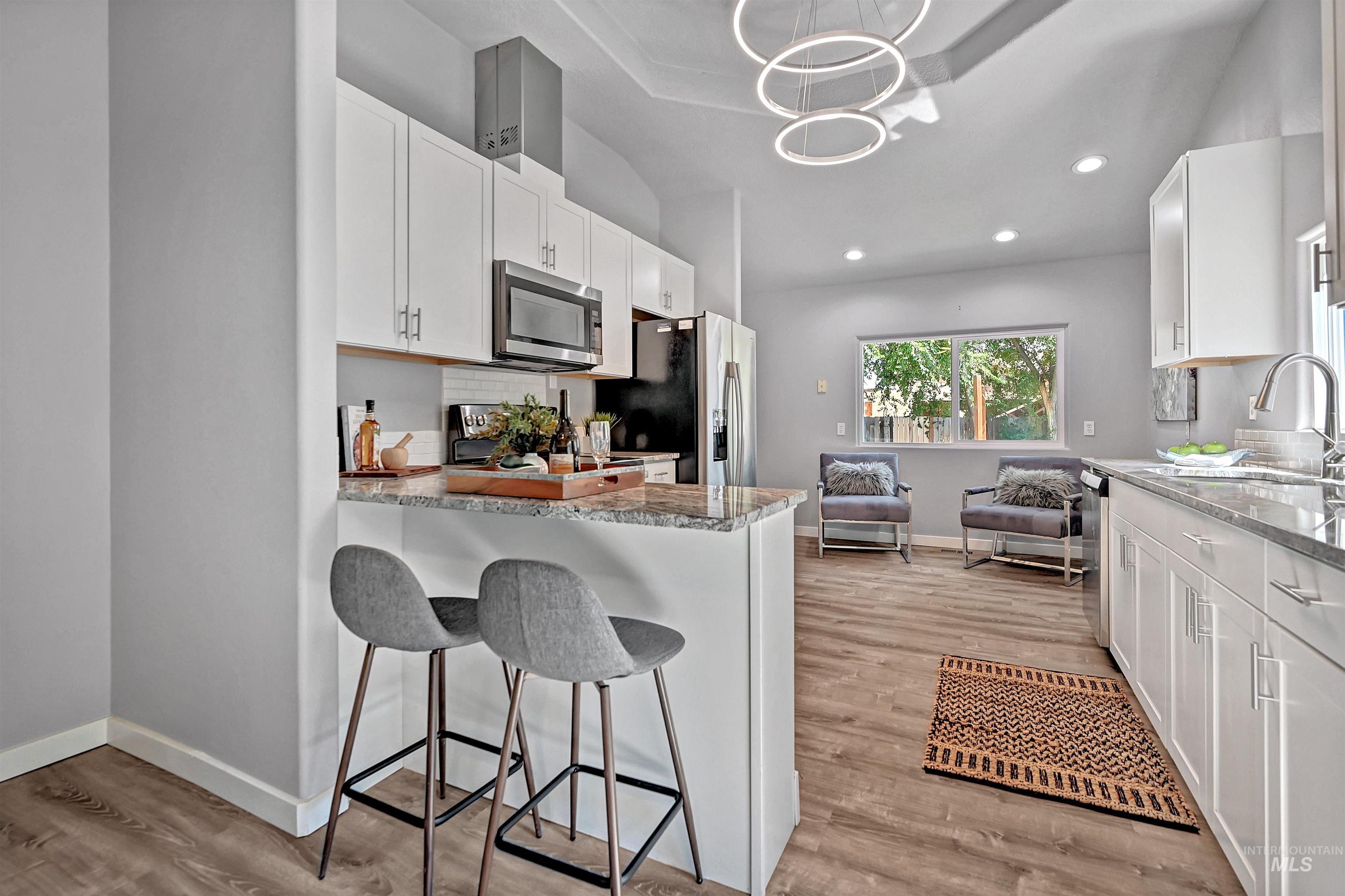 Kitchen featuring light stone countertops, white cabinetry, a breakfast bar area, recessed lighting, and vaulted ceiling