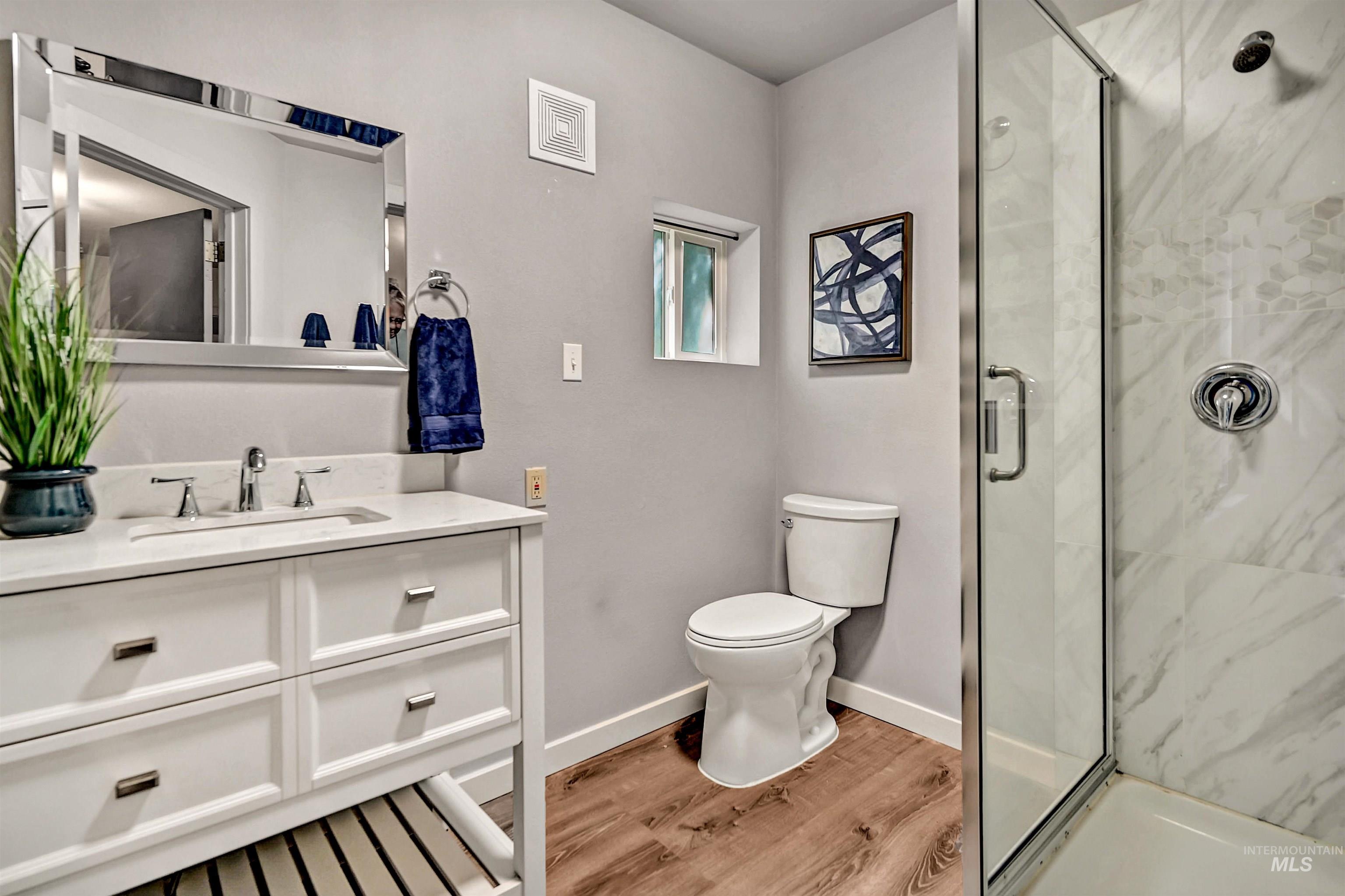 Full bathroom with light wood-style flooring, a marble finish shower, and vanity