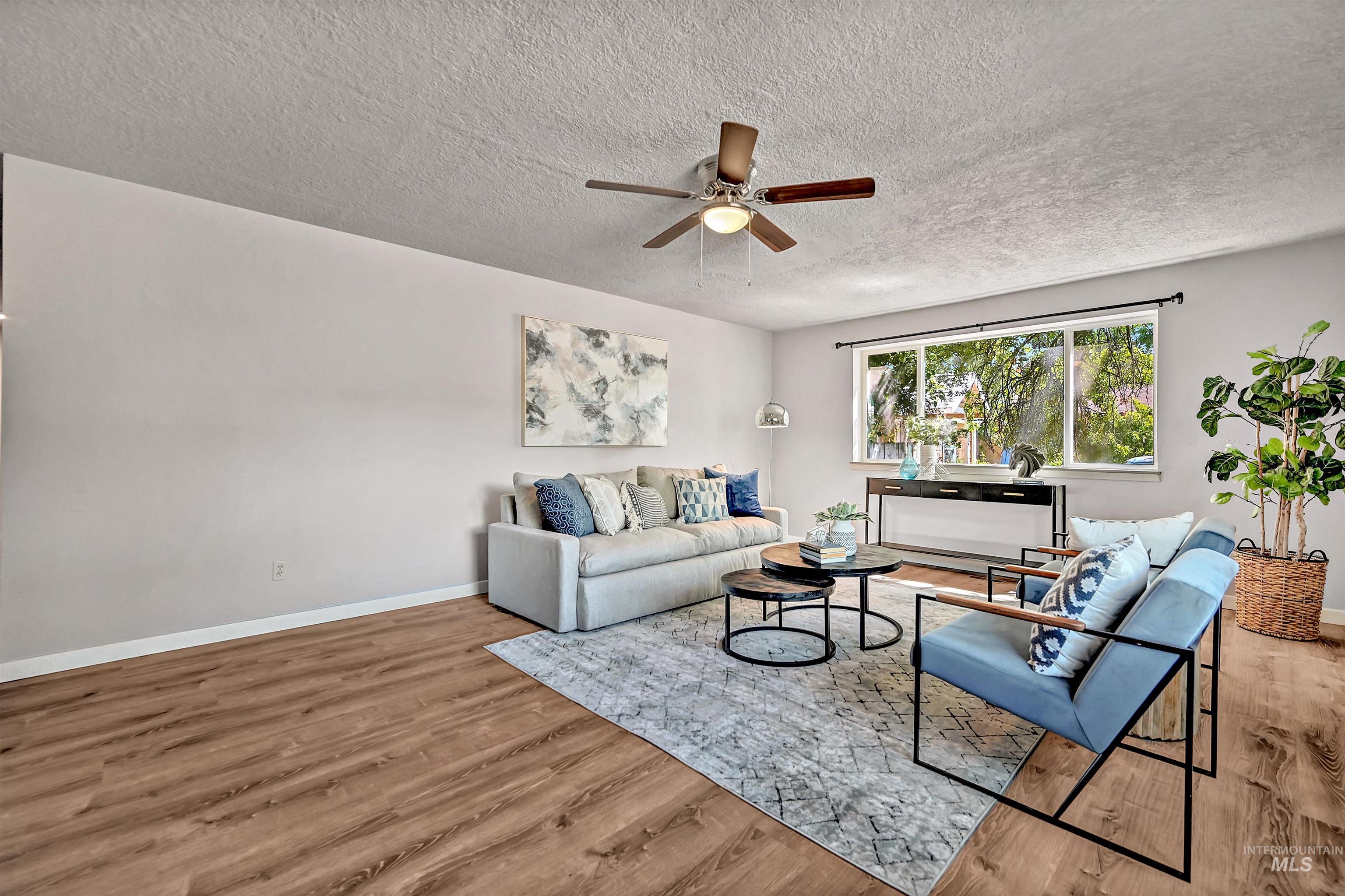 Living room with wood finished floors, a textured ceiling, and ceiling fan