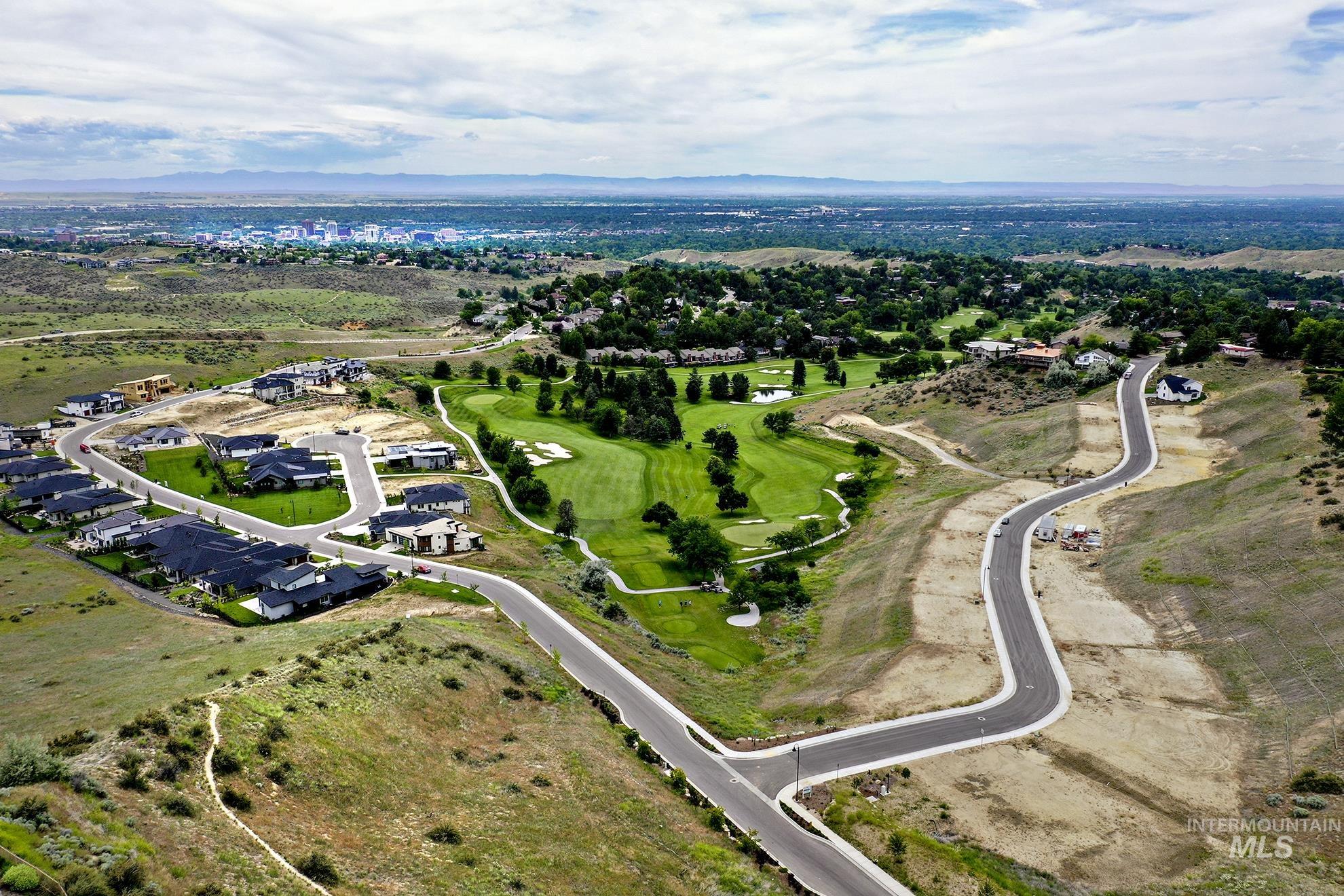 Aerial view of property and surrounding area featuring a mountainous background and nearby suburban area