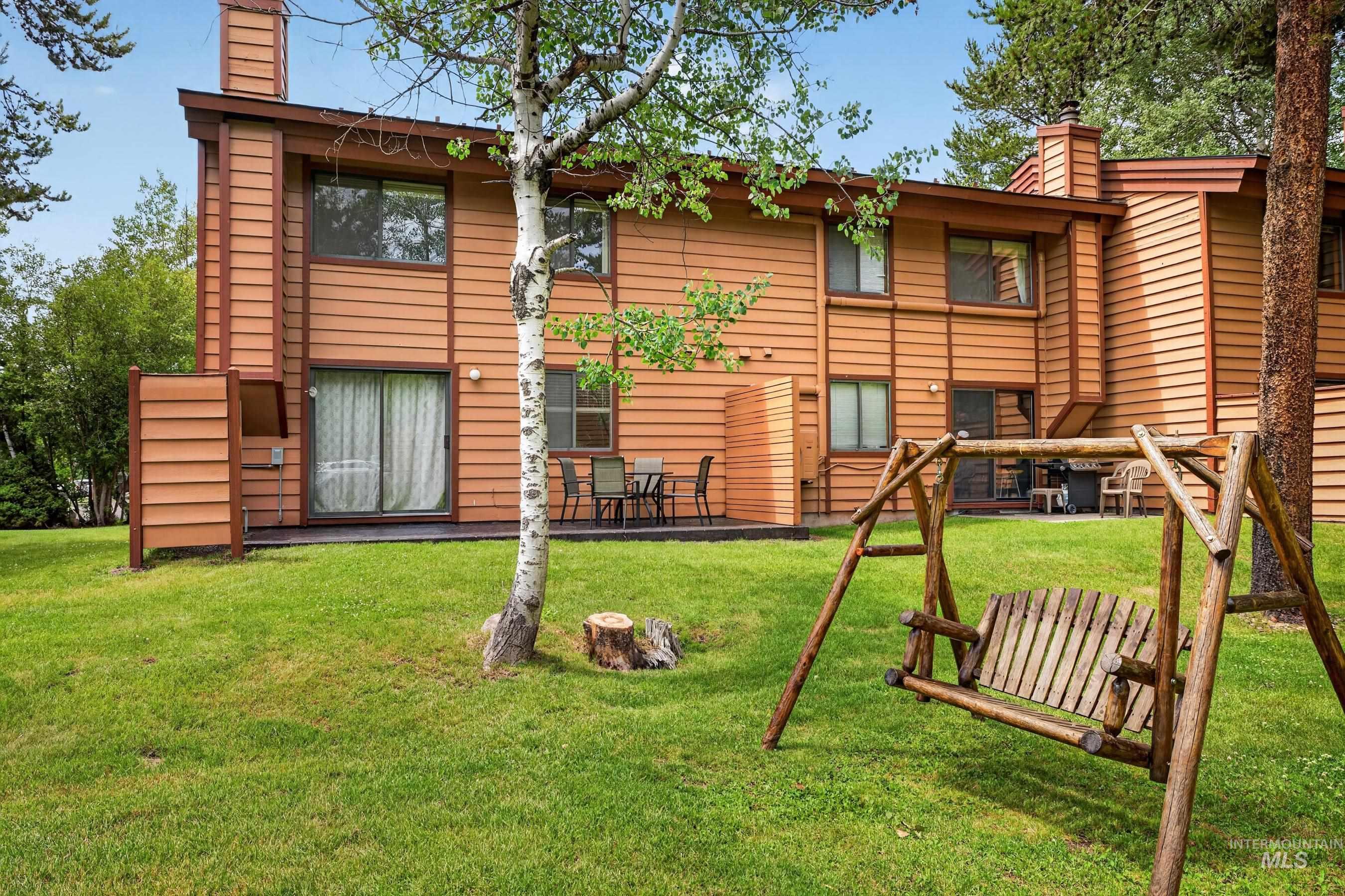 Wood-sided exterior with dual-pane windows and sliding glass doors opening to a ground-level patio