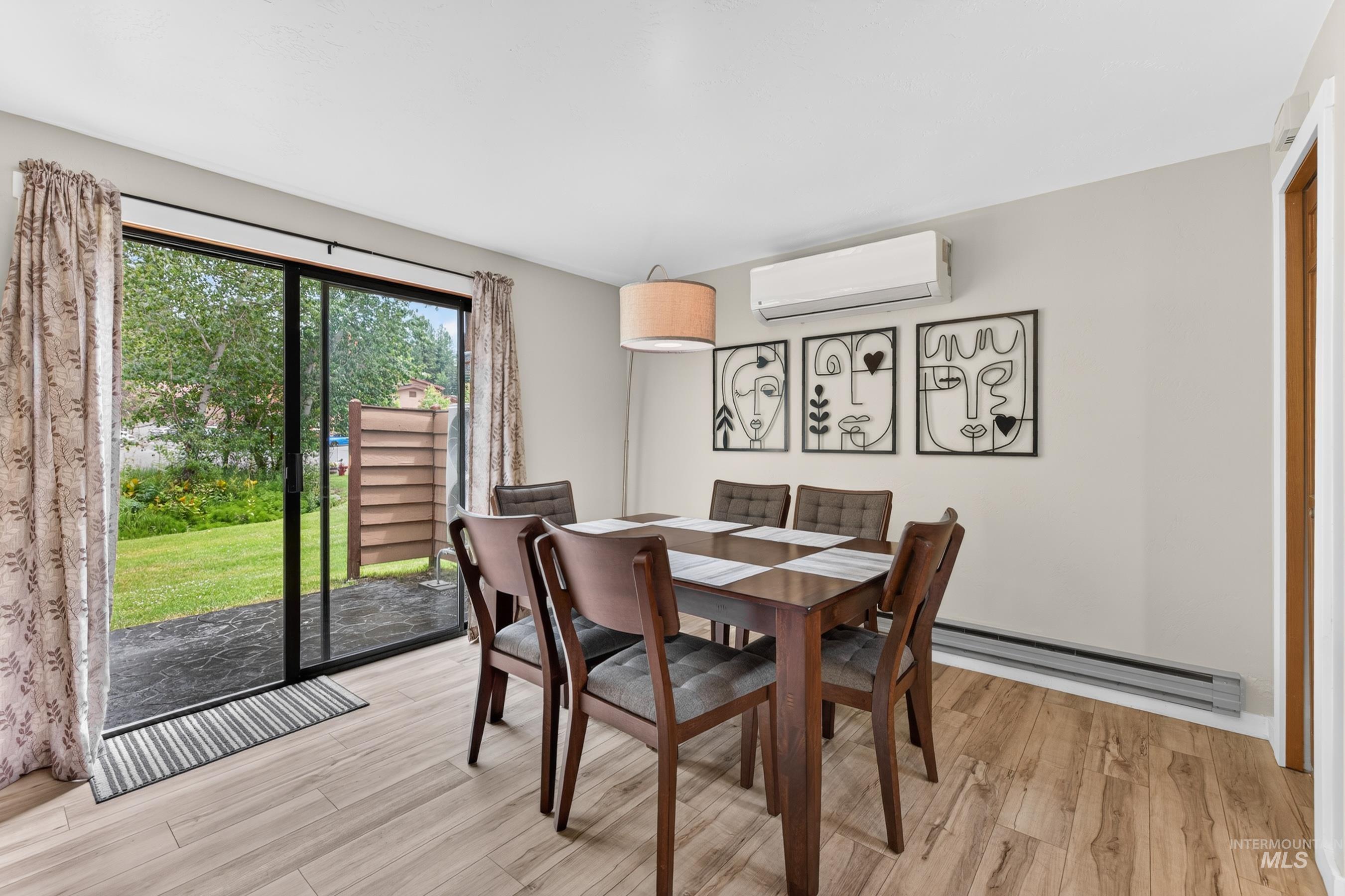 Dining area with wood-finish flooring, sliding glass door, and wall-mounted air conditioning unit