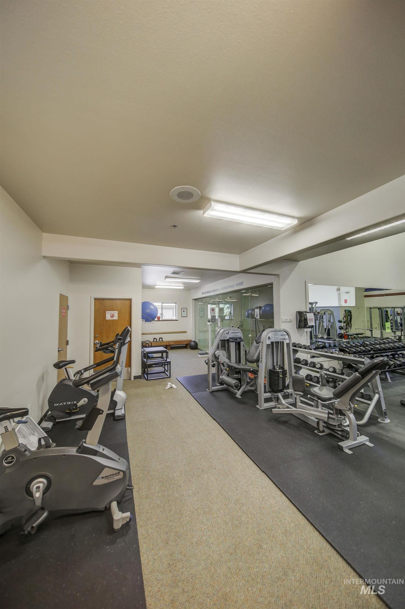 Fitness center featuring cardio and strength training equipment, mirrored wall, and recessed lighting