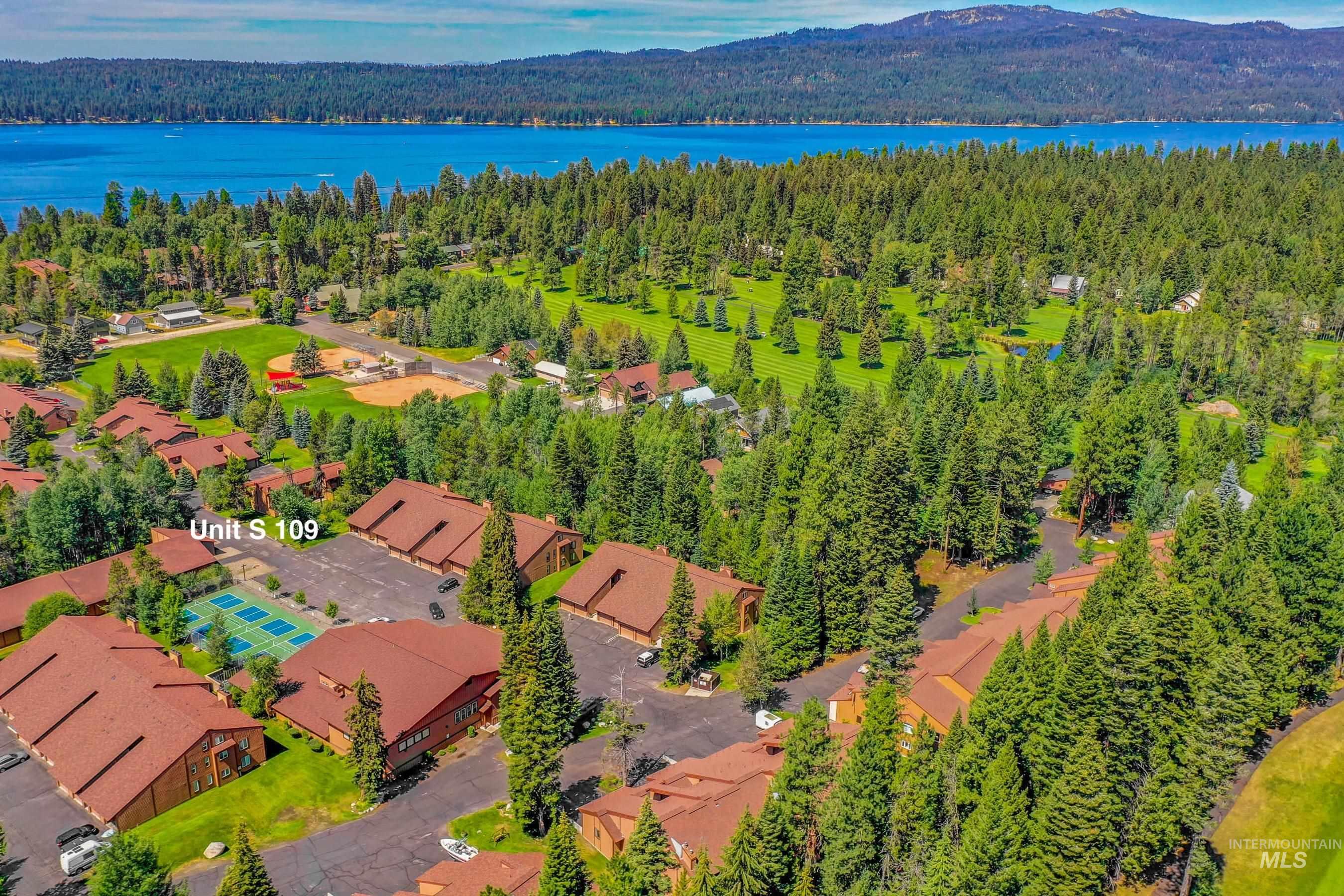 Aerial representation of a residential complex with red-tiled roofs, surrounded by dense evergreen trees and manicured green spaces