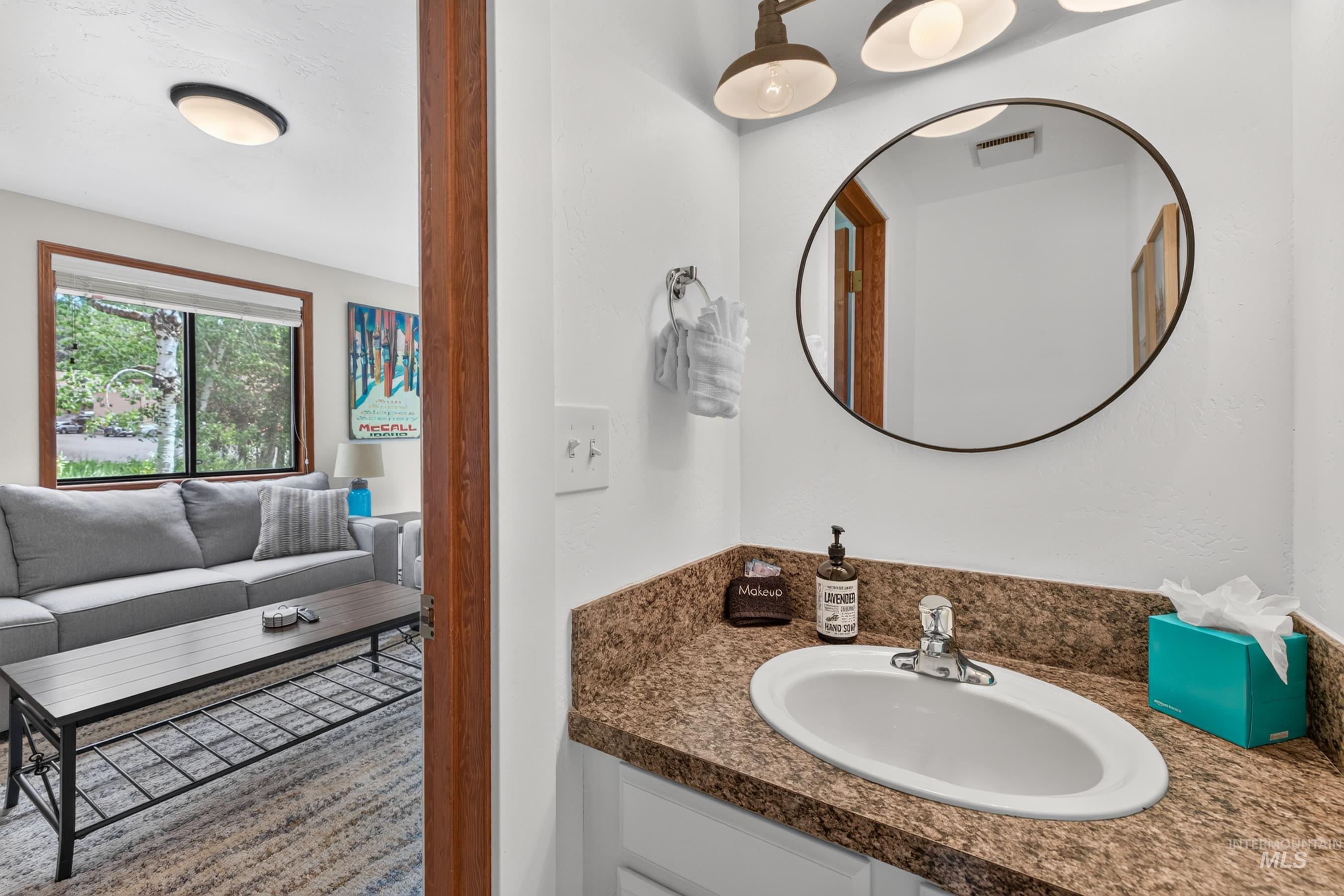 Bathroom vanity with an oval undermount sink, granite-style countertop, and an oval framed mirror