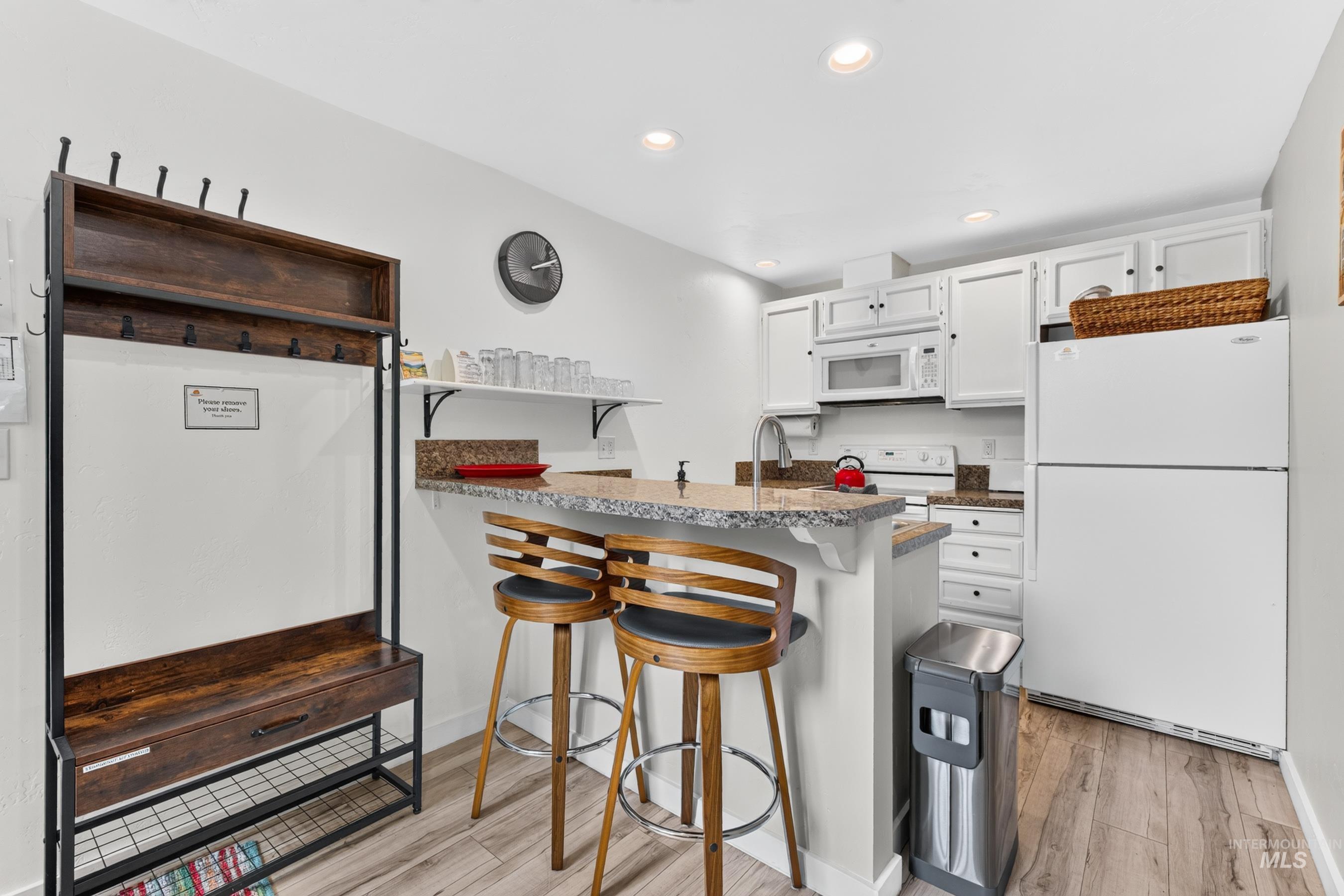 Kitchen space featuring white cabinetry, granite countertops, and wood-finish flooring