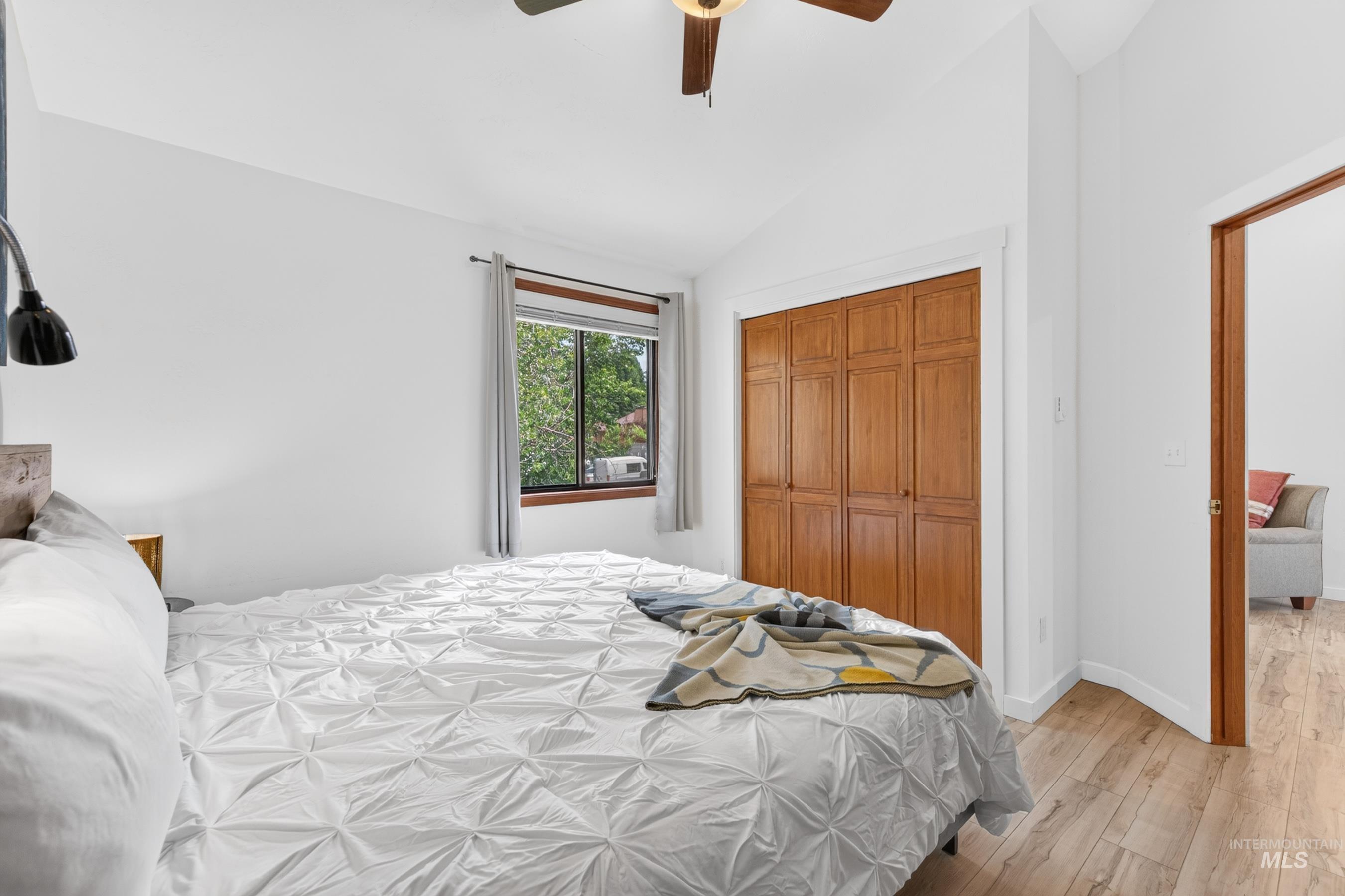 Bedroom with vaulted ceiling, wood-finish flooring, and a ceiling fan