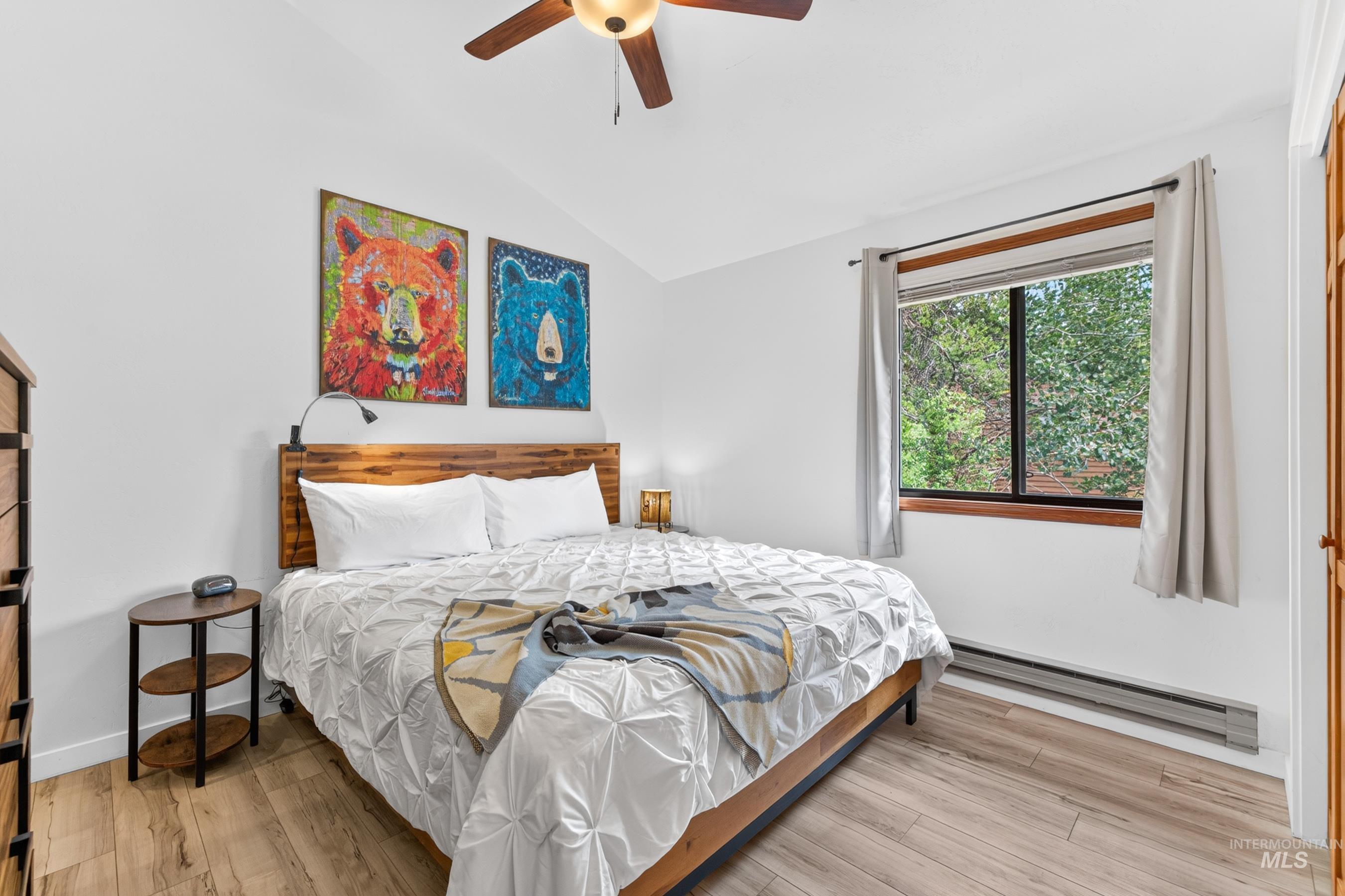 Spacious room featuring wood-finish flooring, a contemporary ceiling fan with integrated lighting, and a large window with white trim