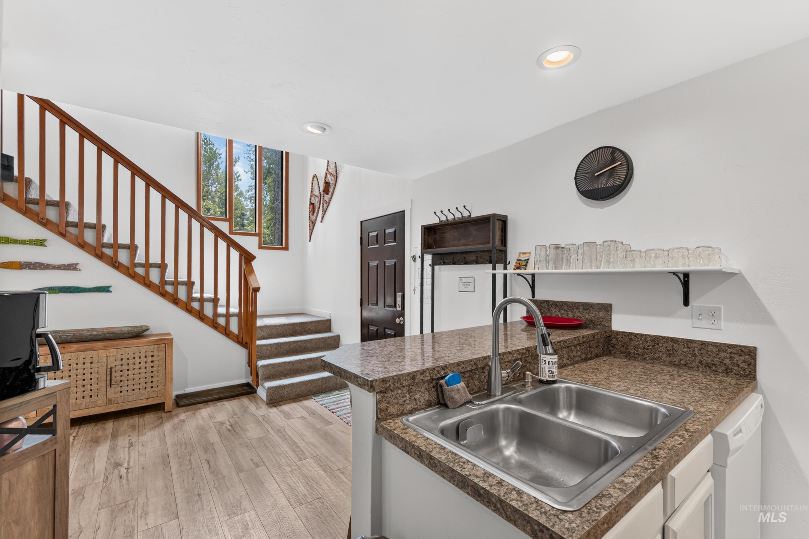 Kitchenette with a stainless steel double sink, speckled countertop, and white cabinetry