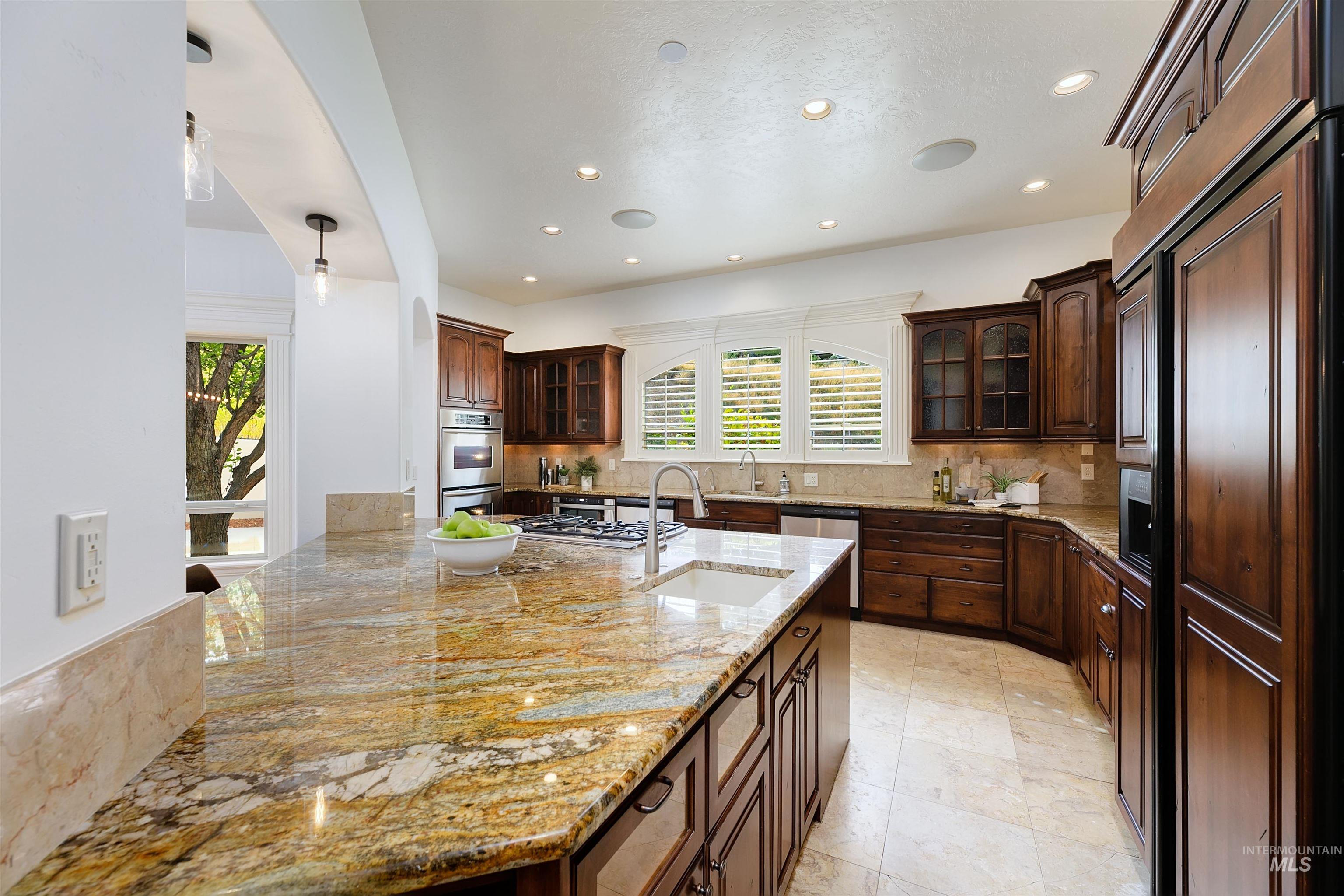 Kitchen featuring decorative backsplash, glass insert cabinets, light stone counters, and recessed lighting