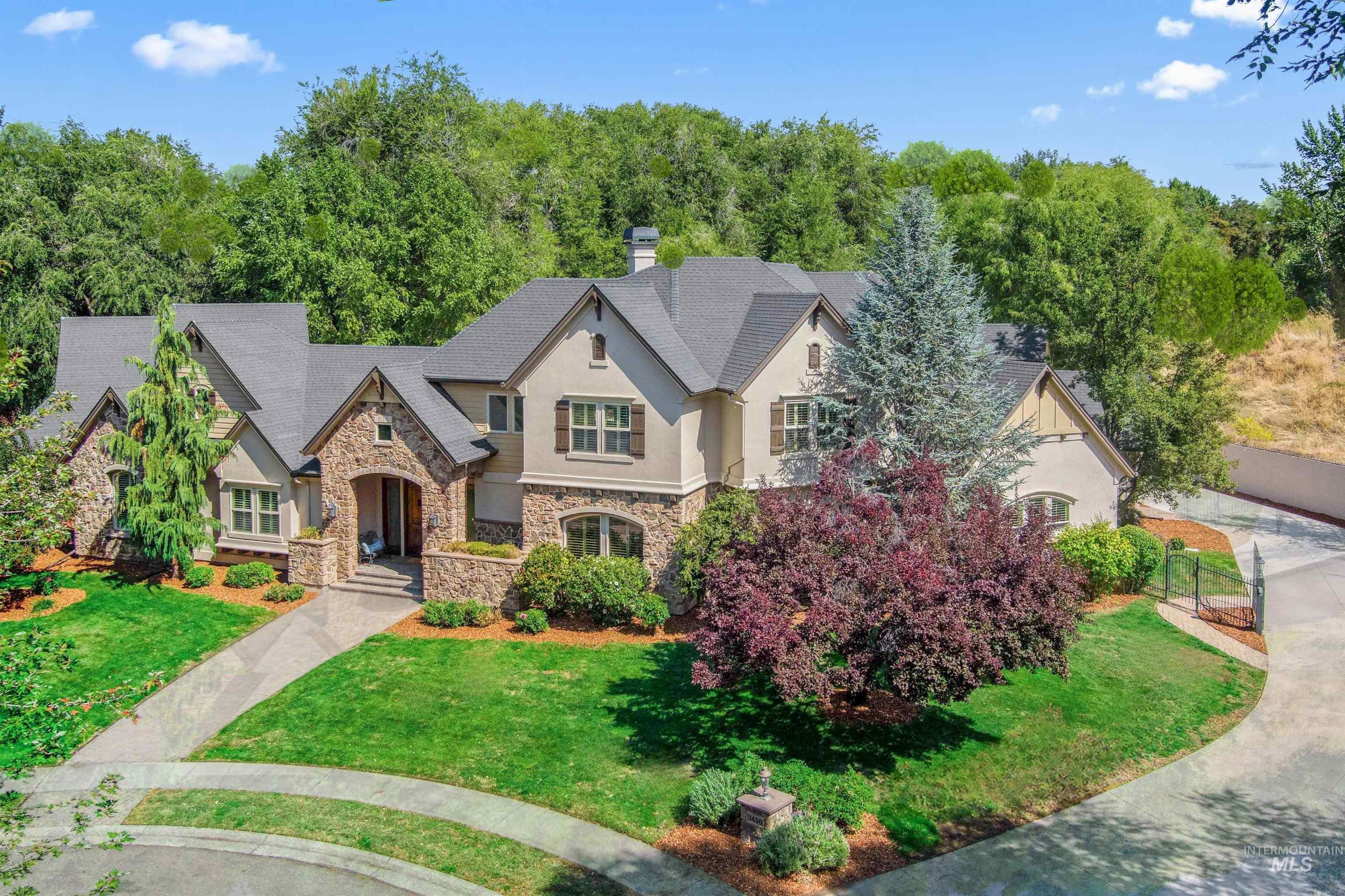 View of front of home with stone siding, a front yard, stucco siding, and a chimney