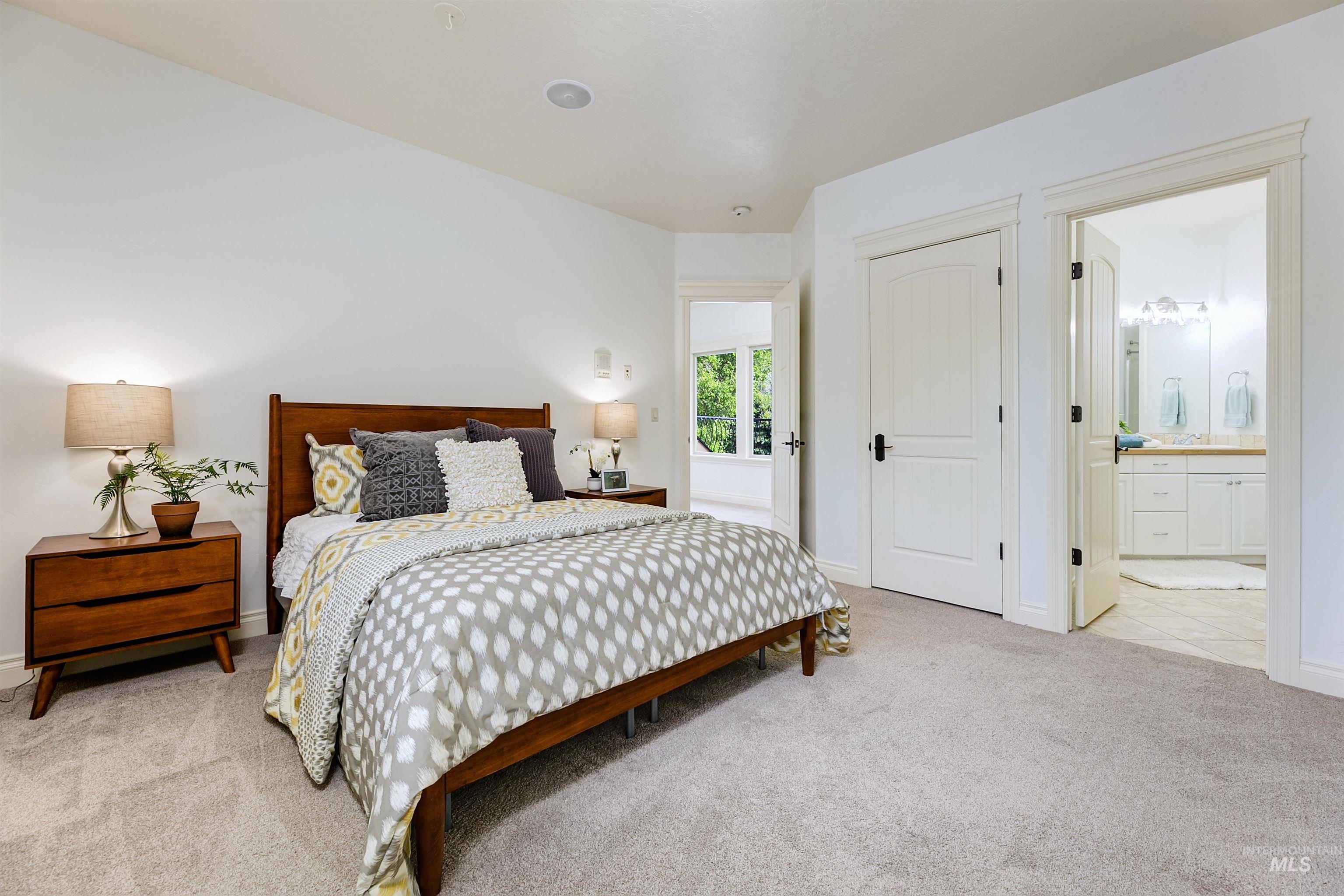 Bedroom featuring light carpet, a closet, and ensuite bathroom