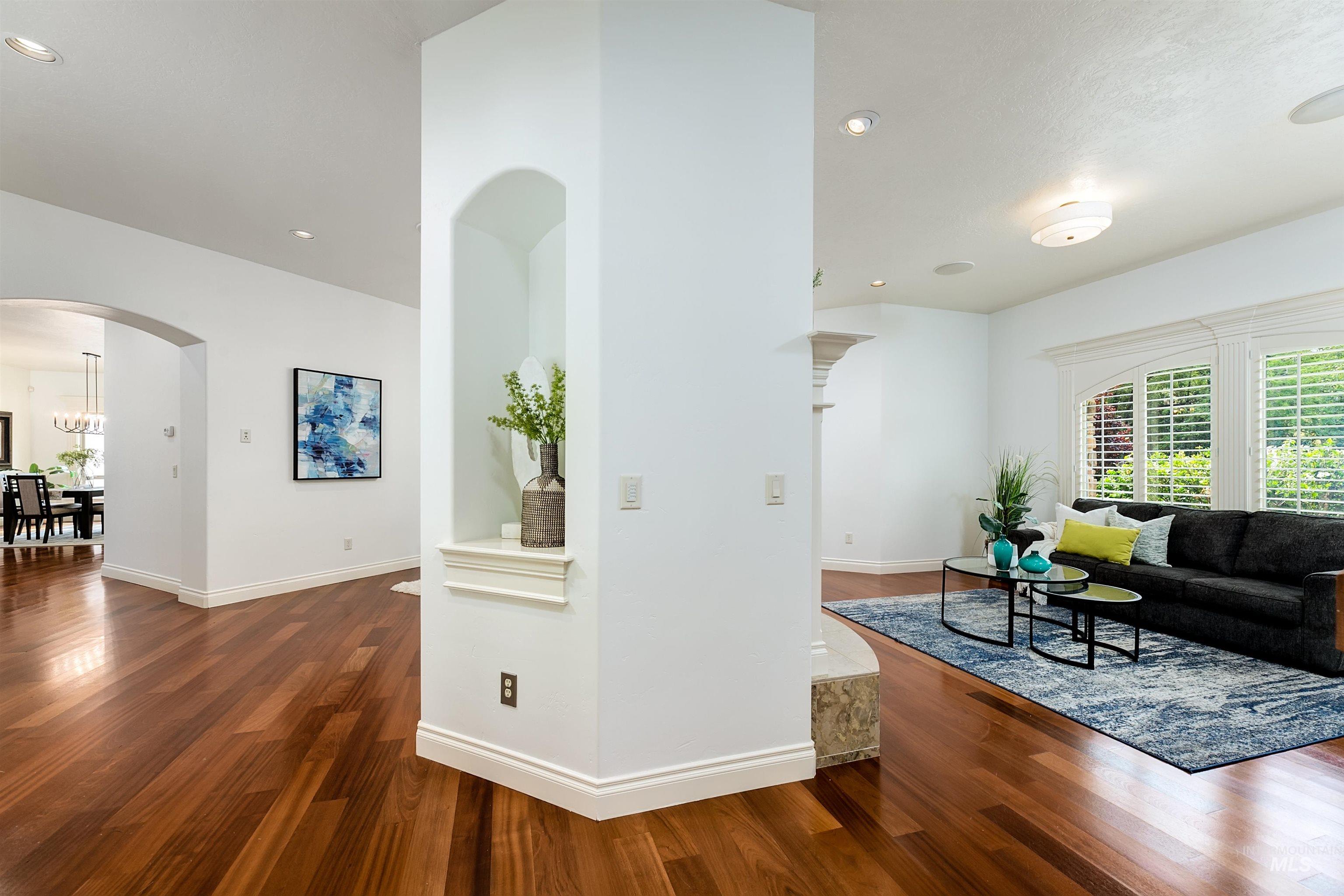 Living room with arched walkways, dark wood-style floors, and recessed lighting