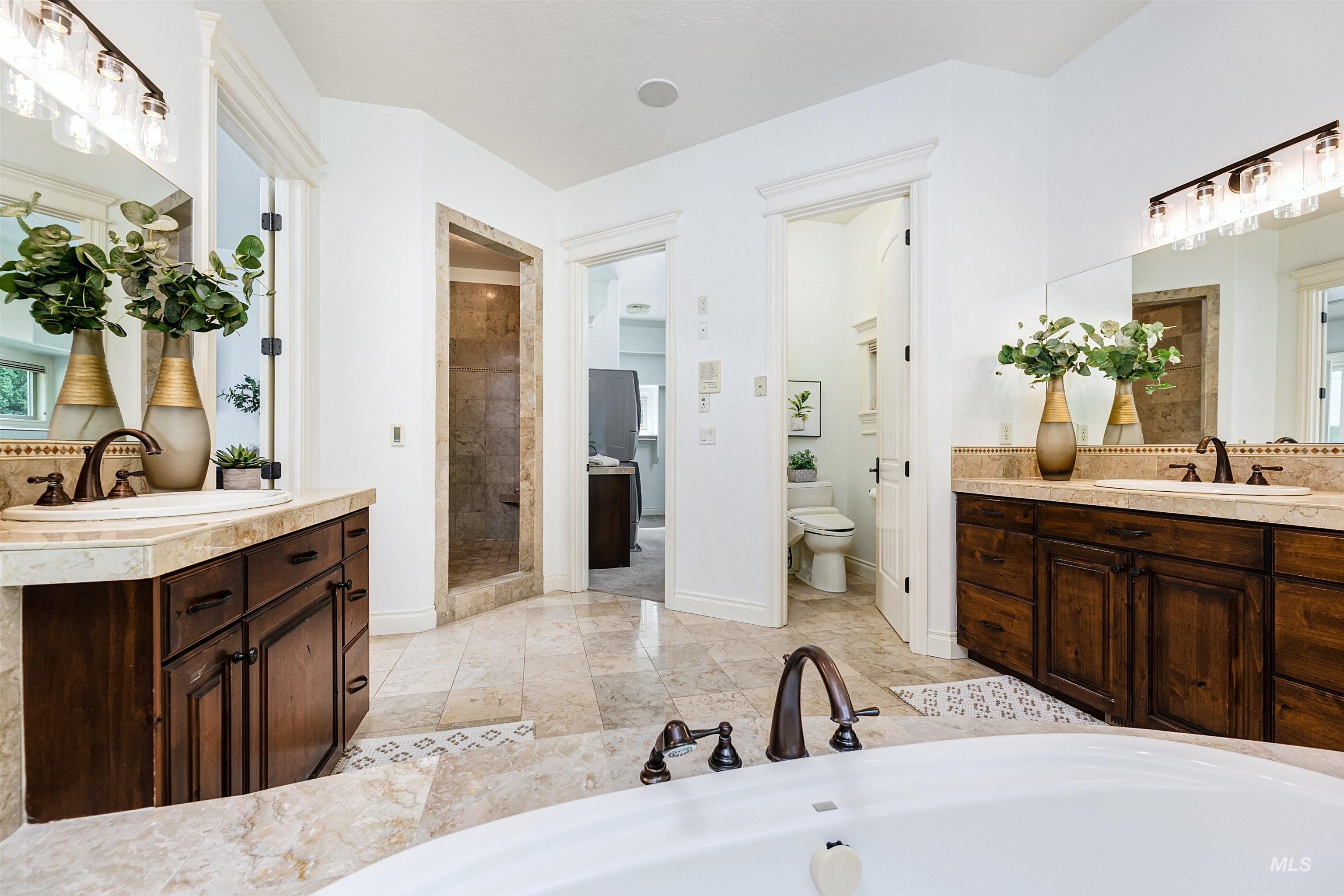 Full bath with two vanities, a shower stall, decorative backsplash, and a garden tub