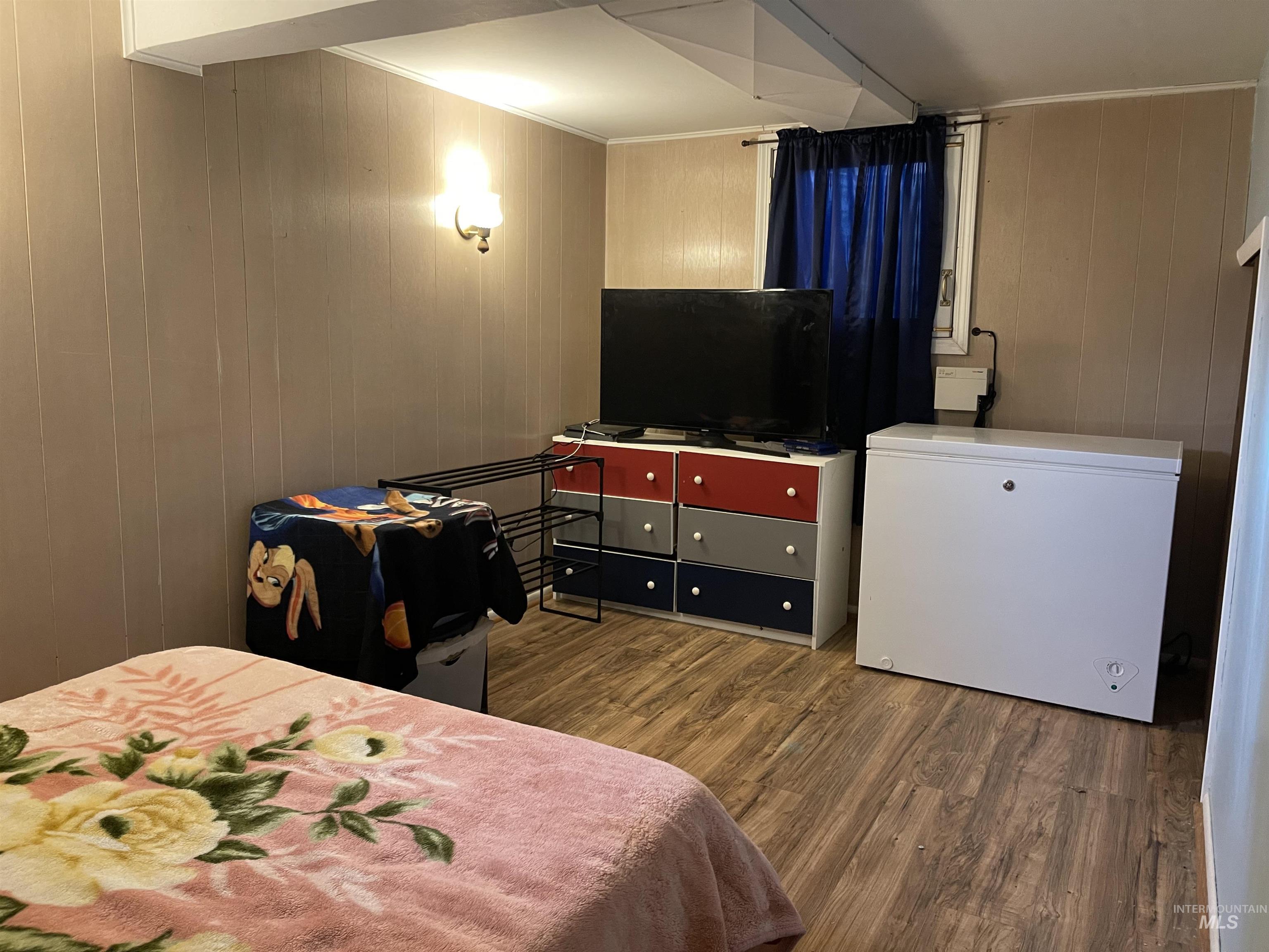 Bedroom with wood finished floors, crown molding, and wooden walls
