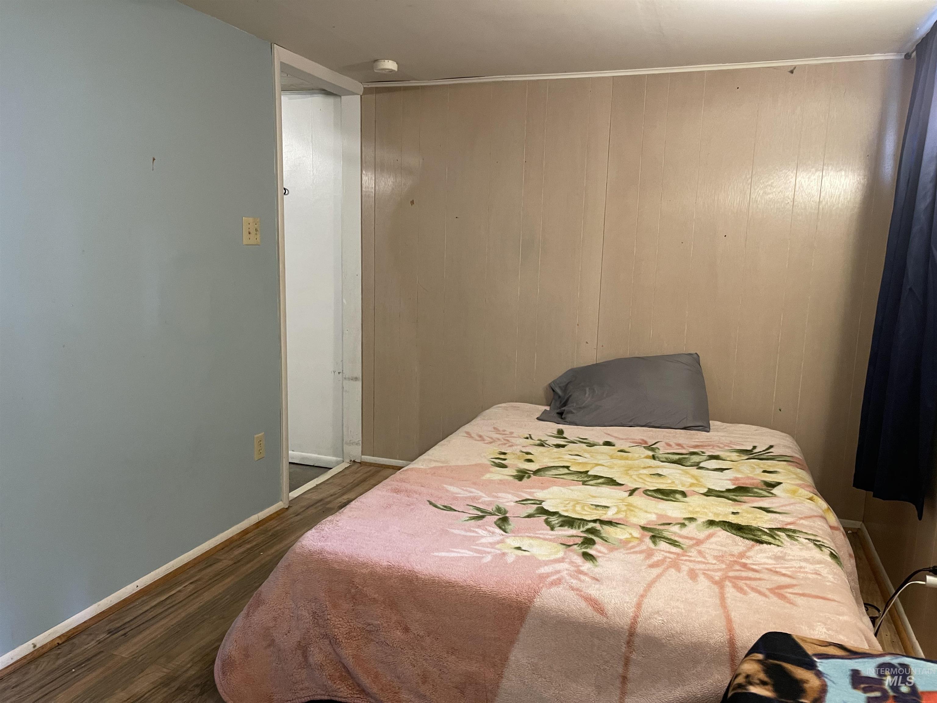 Bedroom with dark wood-type flooring and wood walls