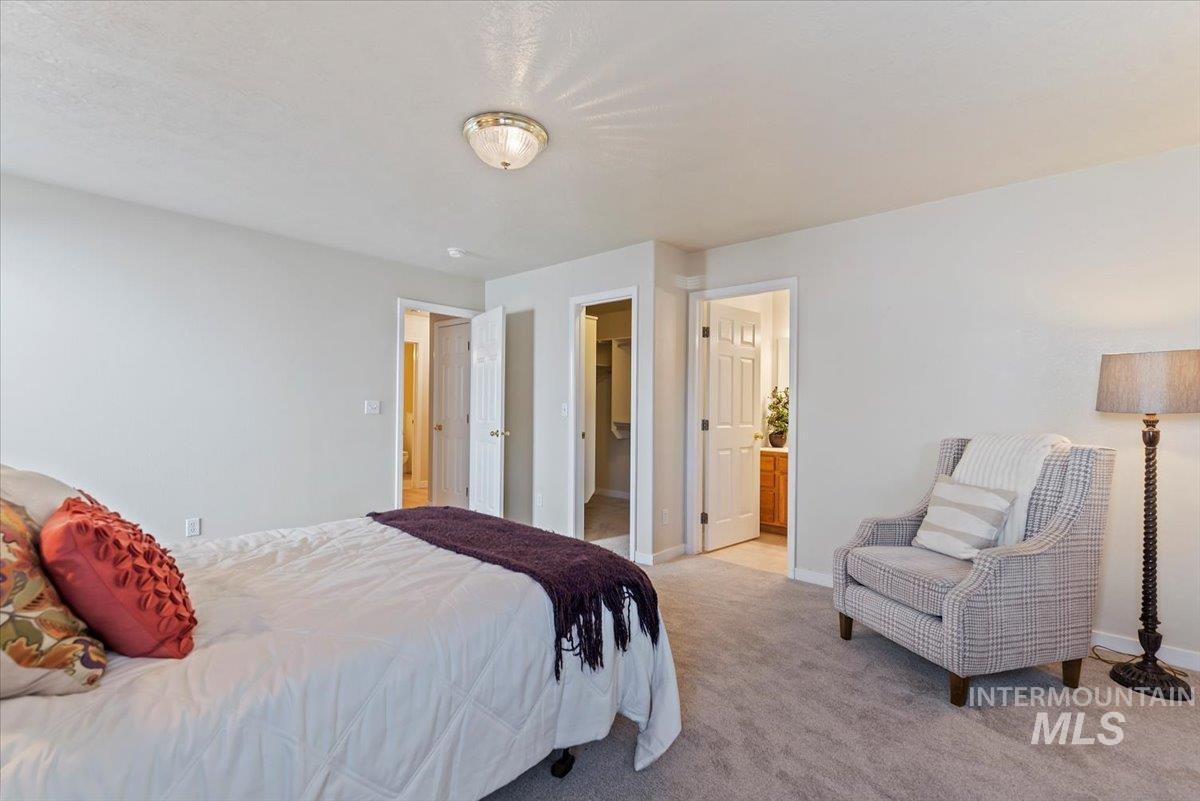 Bedroom featuring ensuite bathroom, light colored carpet, and a spacious closet