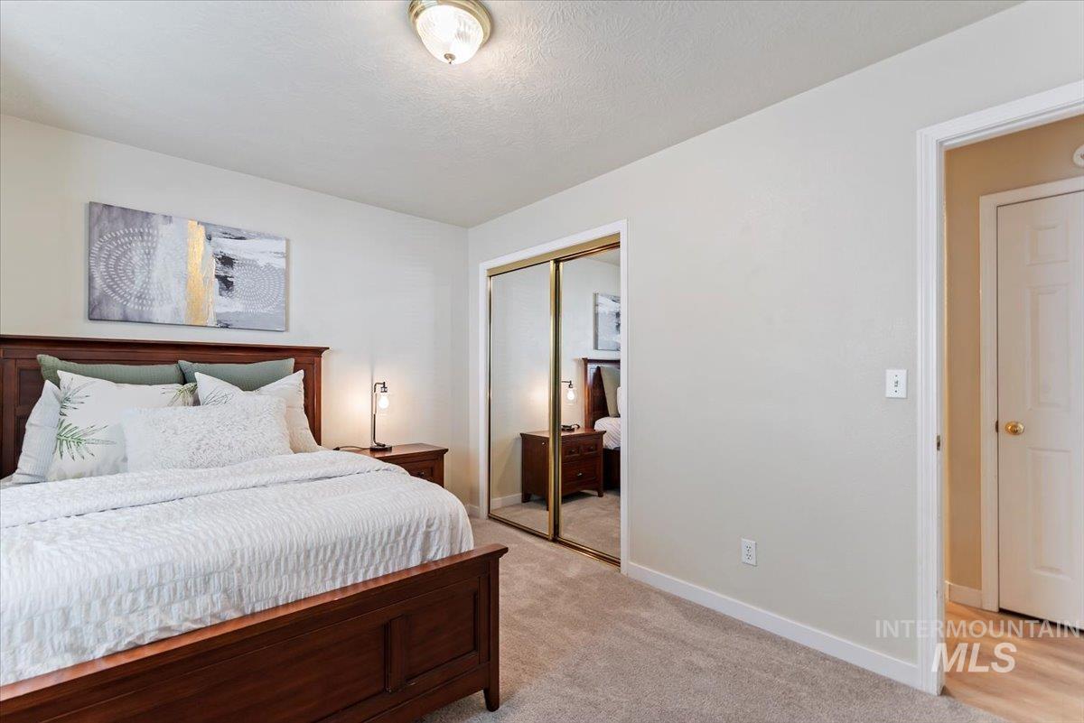Bedroom with light carpet, a closet, and a textured ceiling