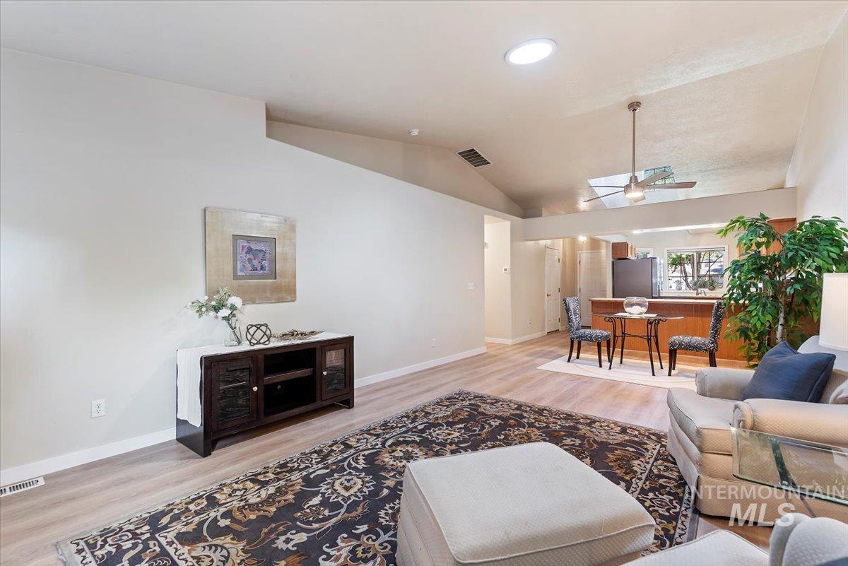 Living room with light wood finished floors, vaulted ceiling, a ceiling fan, and recessed lighting