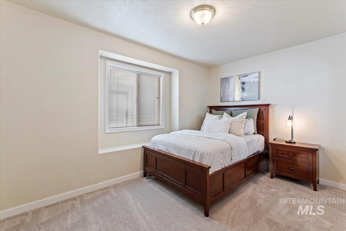 Bedroom with a textured ceiling and light colored carpet