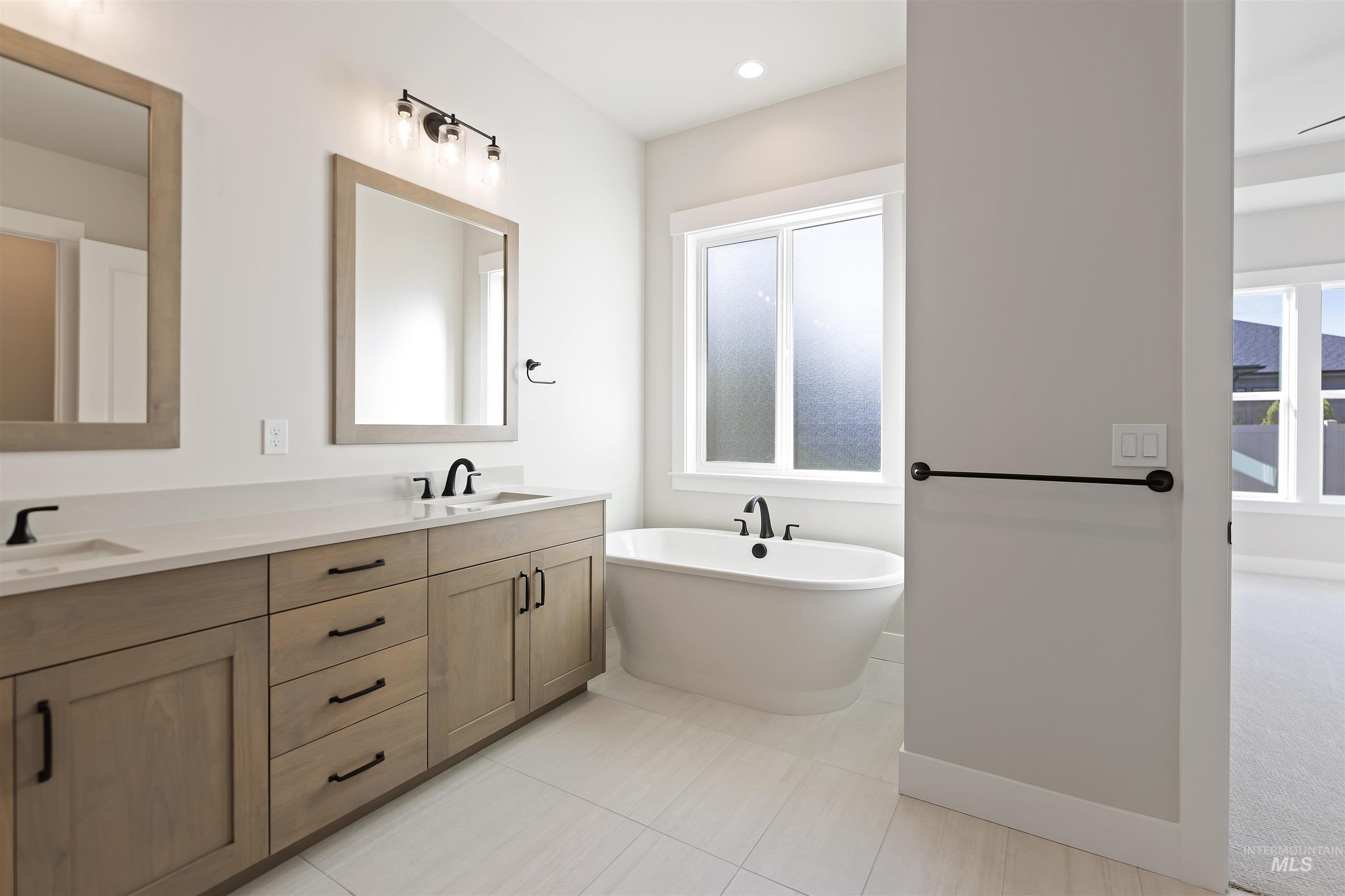 Bathroom with double vanity, a soaking tub, light tile patterned floors, and recessed lighting