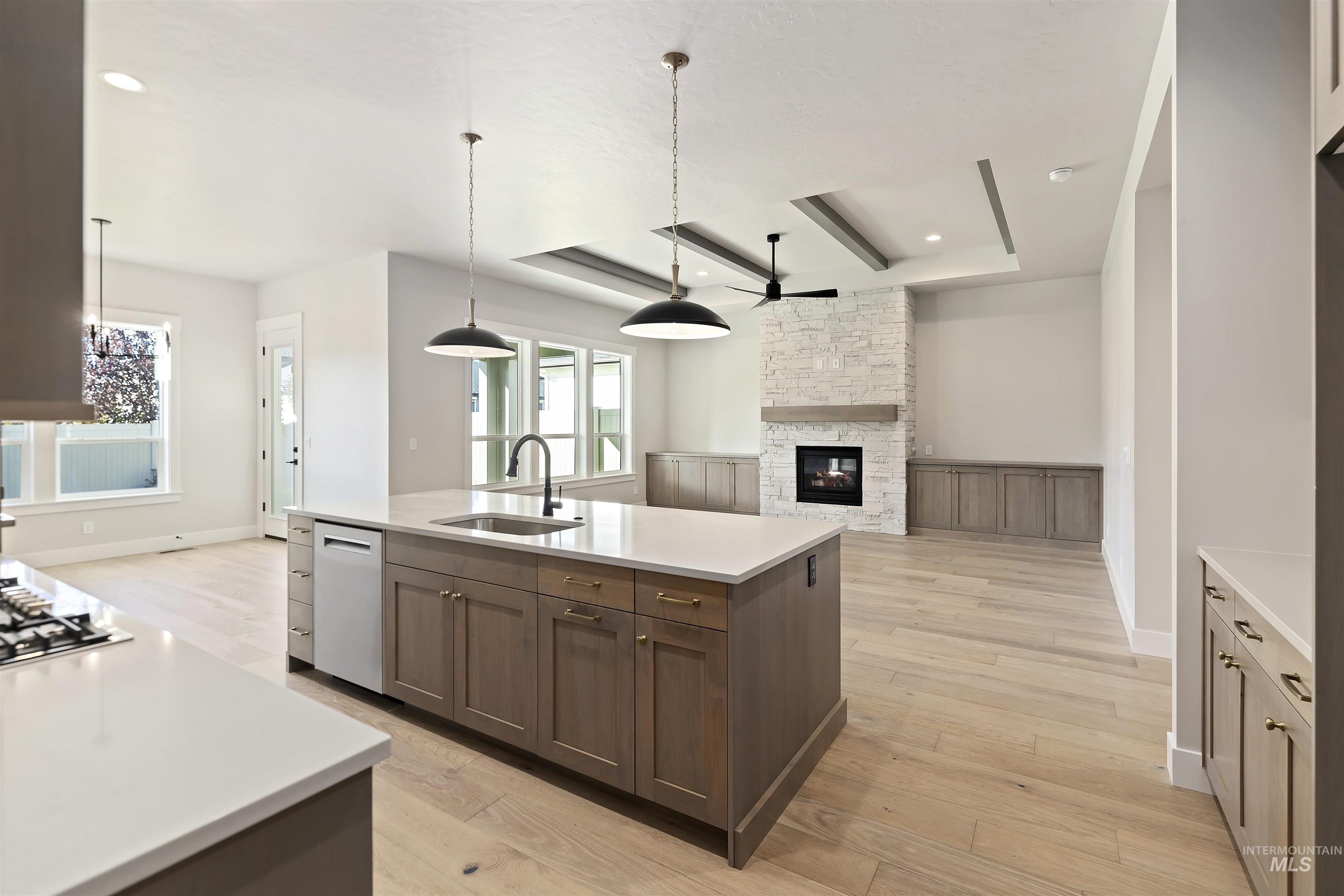 Kitchen featuring pendant lighting, open floor plan, a ceiling fan, a raised ceiling, and recessed lighting