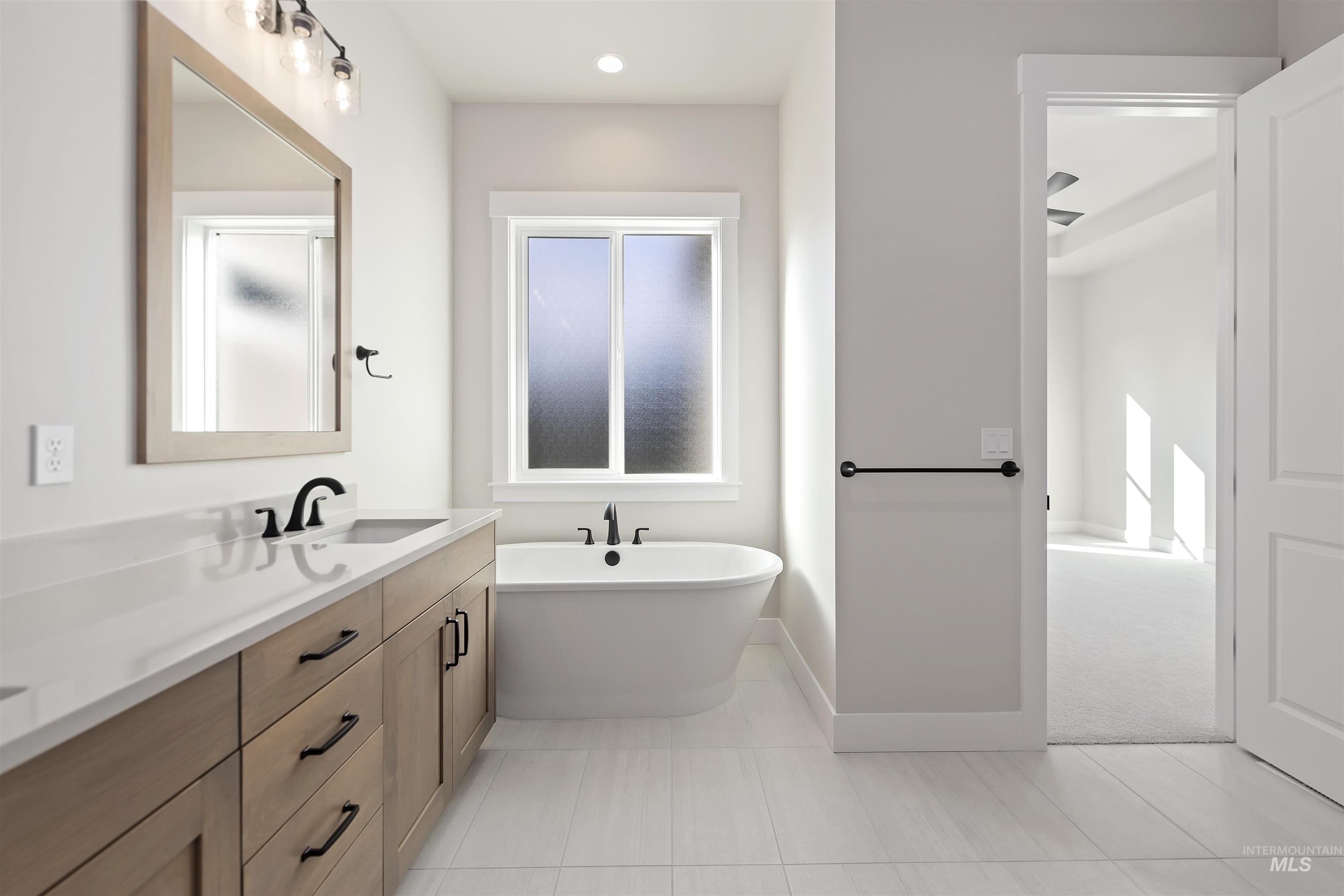 Bathroom featuring double vanity, a freestanding tub, light tile patterned floors, recessed lighting, and light carpet