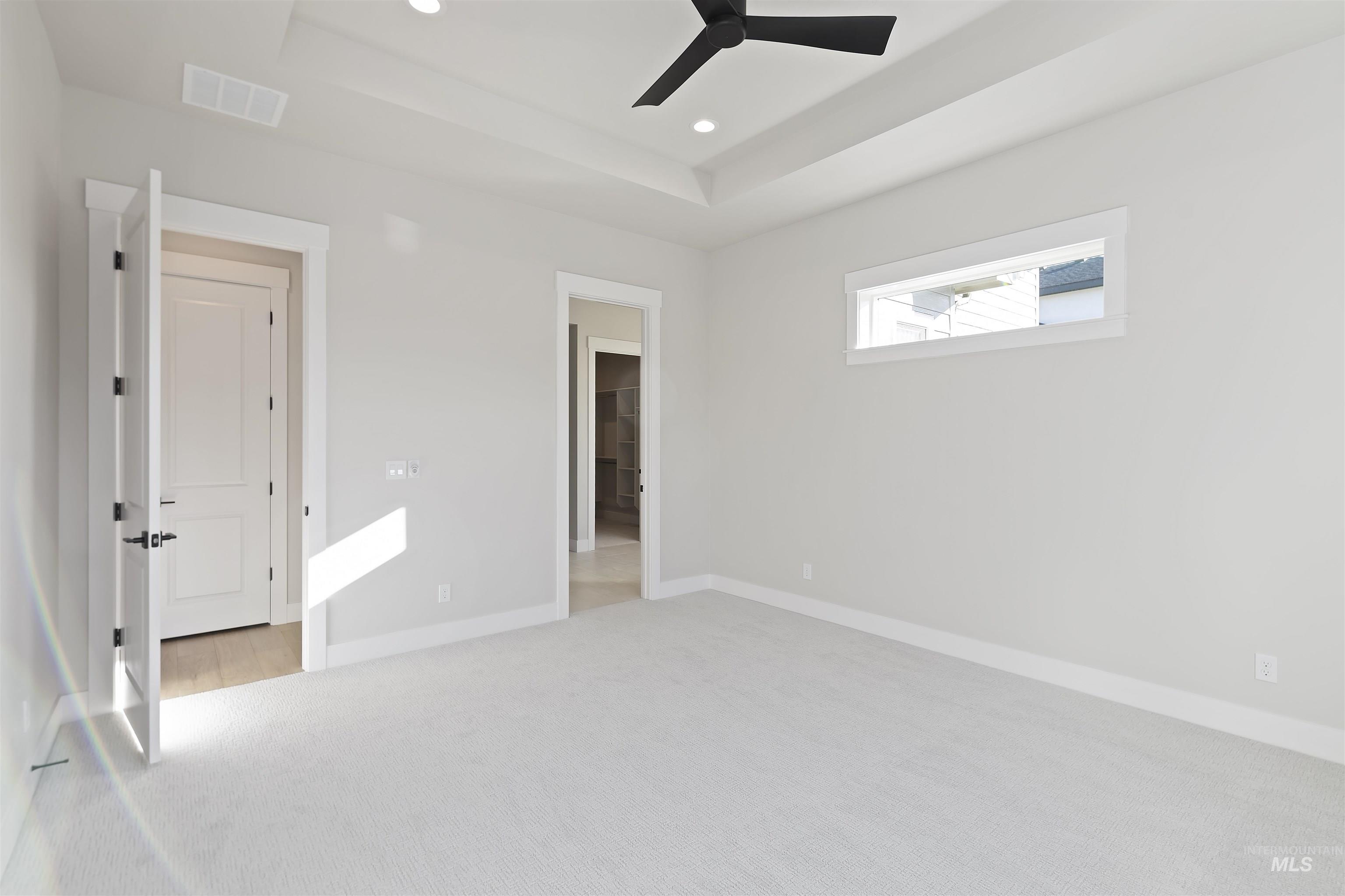 Featuring a raised ceiling, carpet flooring, ceiling fan, and recessed lighting