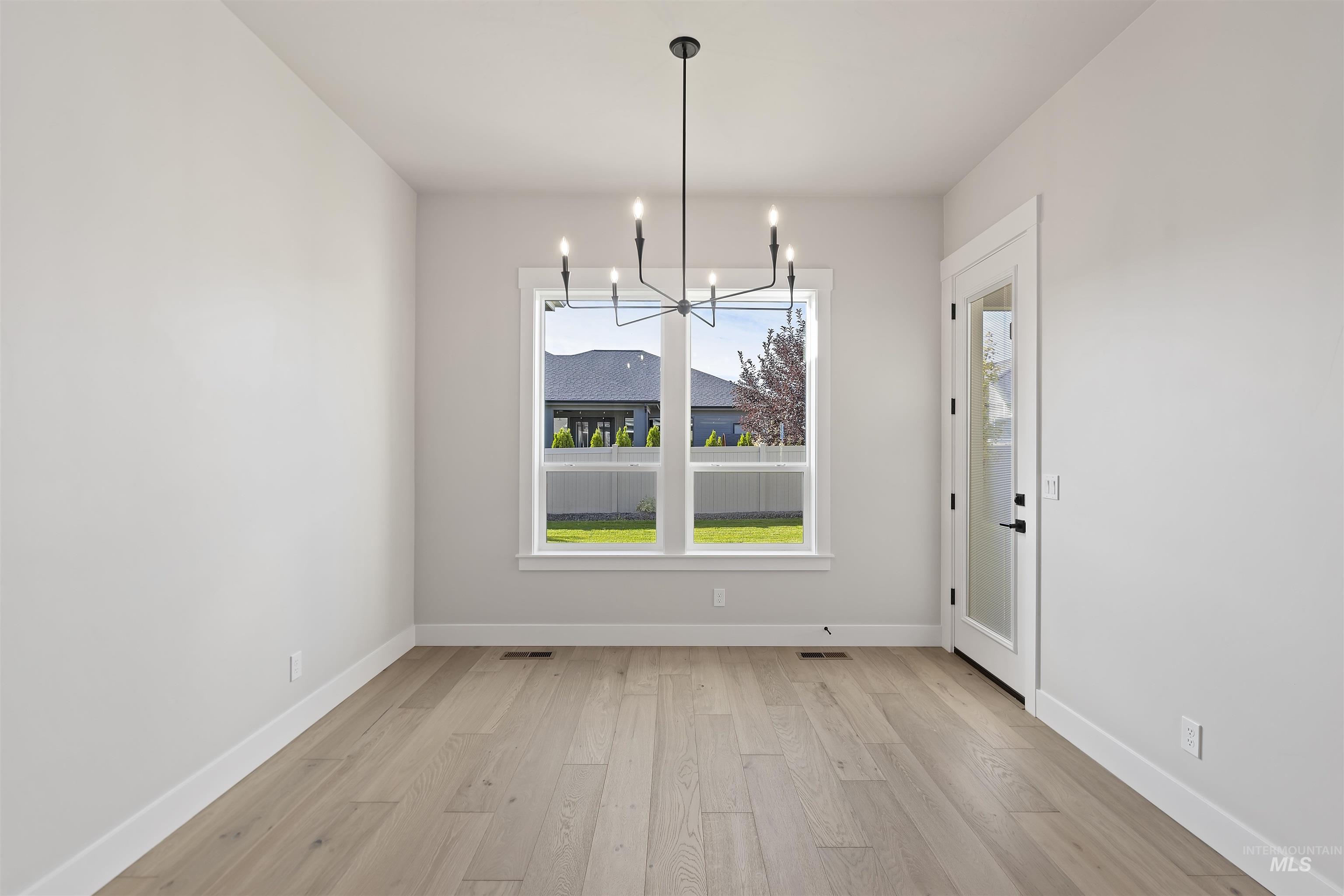 Unfurnished dining area with light wood-style flooring and a chandelier