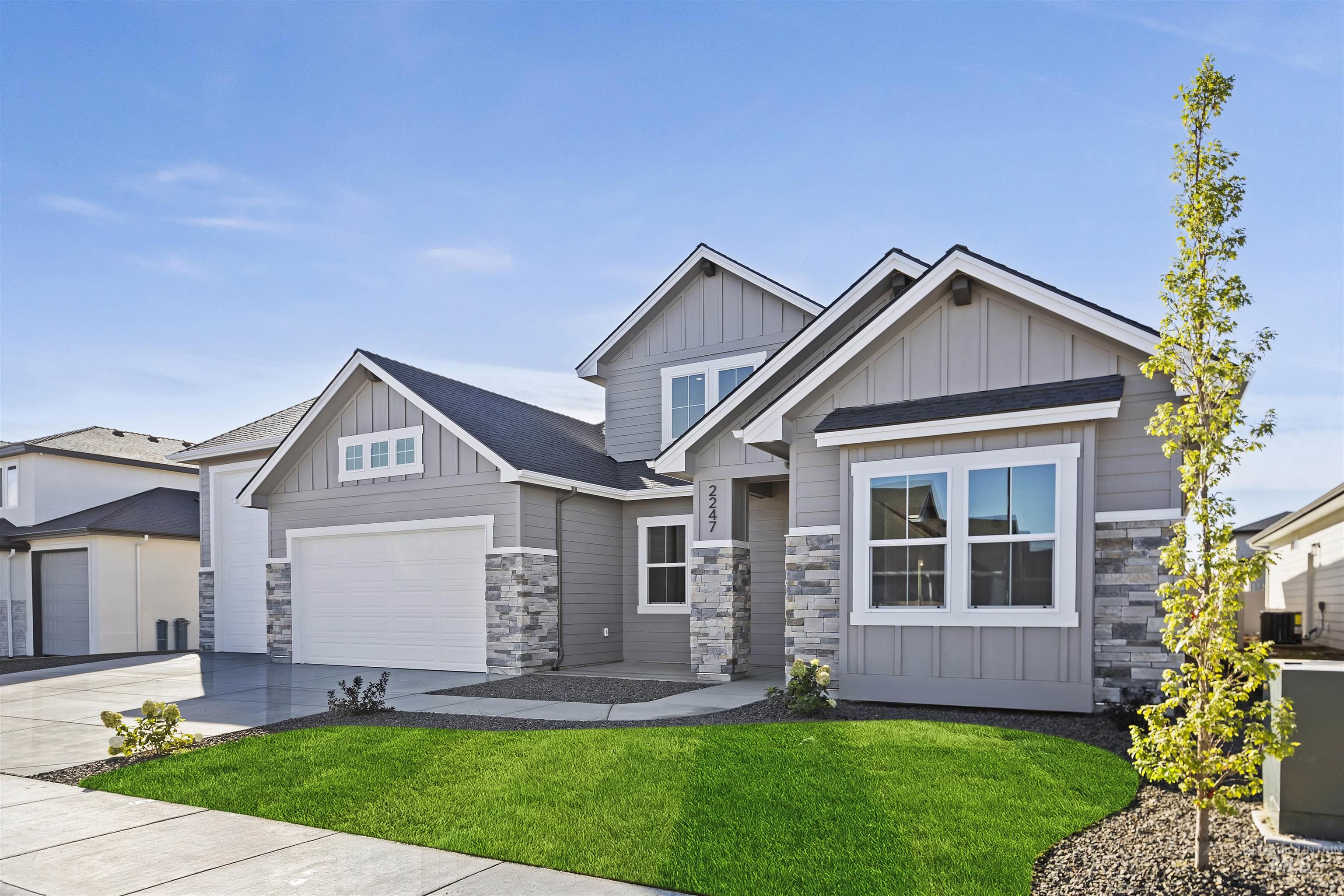 Craftsman-style house featuring board and batten siding, stone siding, a front lawn, and driveway