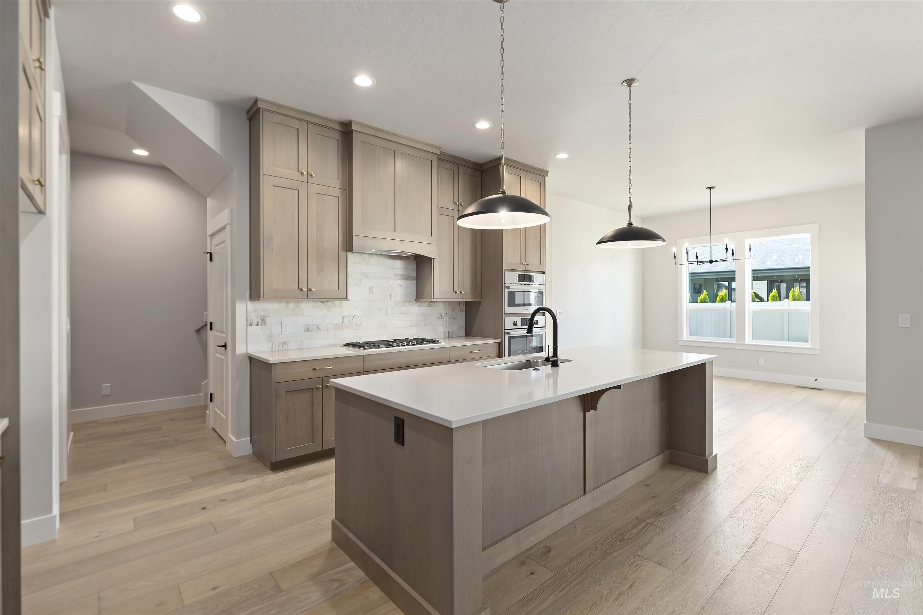 Kitchen with tasteful backsplash, pendant lighting, light wood-type flooring, a kitchen breakfast bar, and recessed lighting