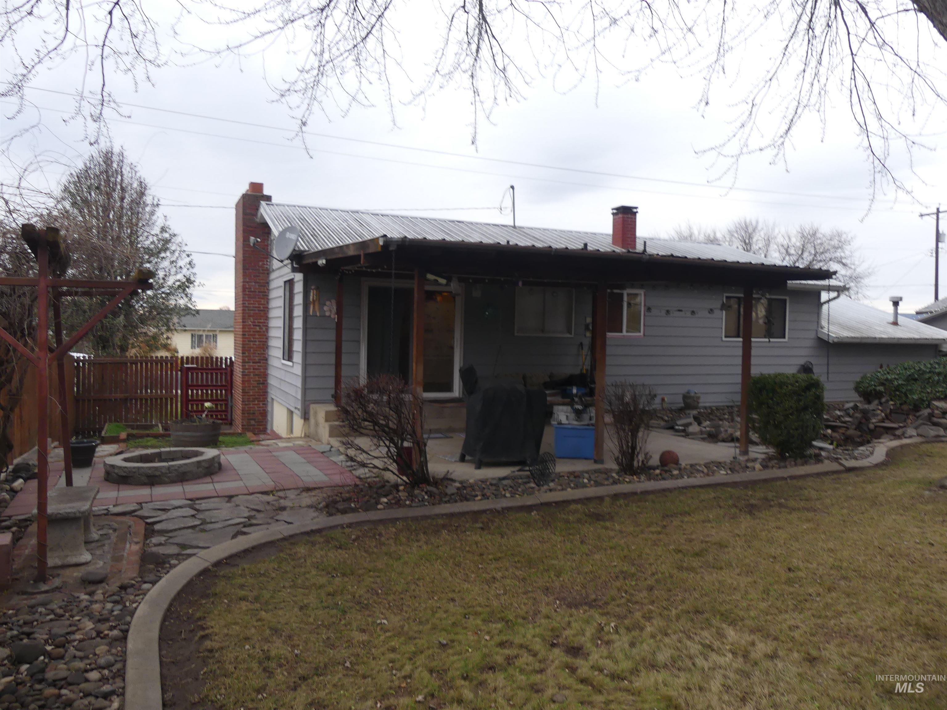 Back of house with a chimney, a fire pit, a patio, and a metal roof