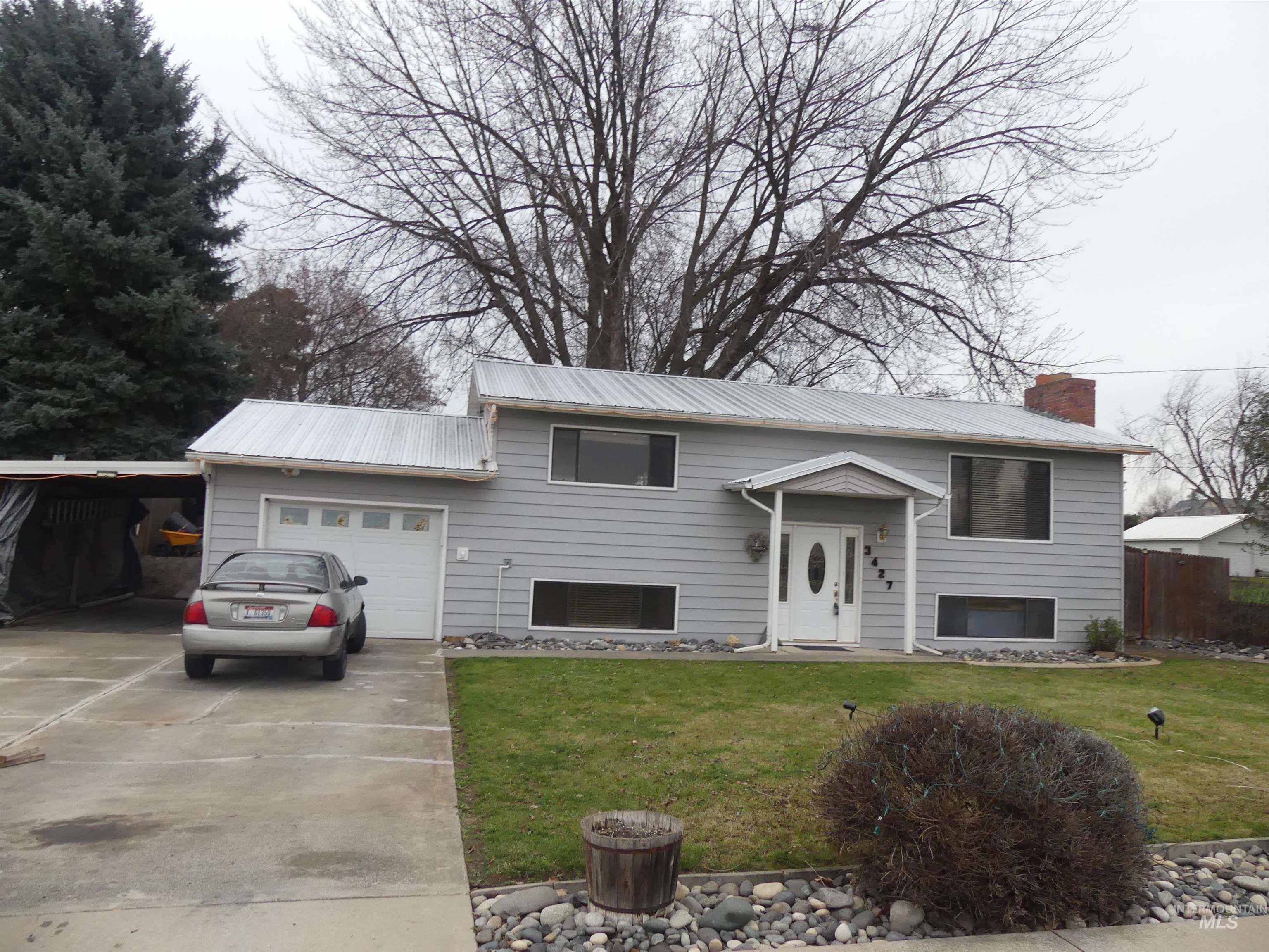 Split foyer home featuring concrete driveway, a garage, a front lawn, and a chimney