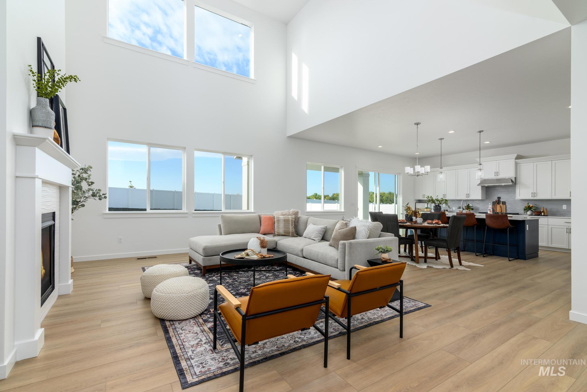 Living area featuring light wood-style flooring, plenty of natural light, a chandelier, and a towering ceiling