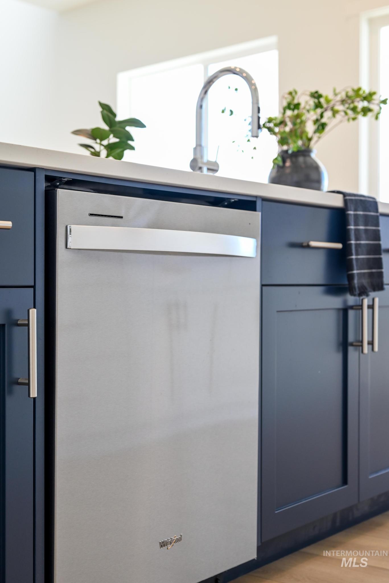 Kitchen view of blue cabinets, dishwasher, light countertops, and light wood-style floors