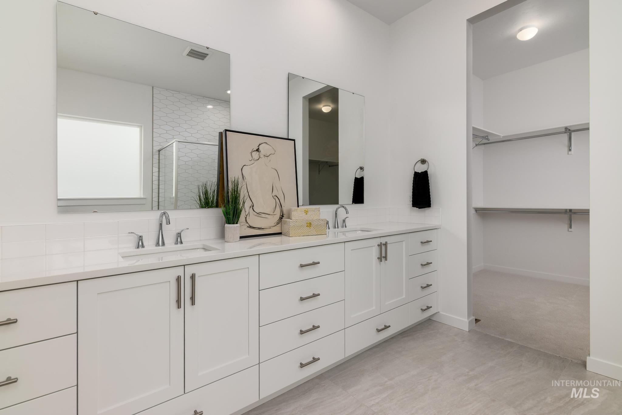 Full bath featuring a stall shower, double vanity, and a walk in closet