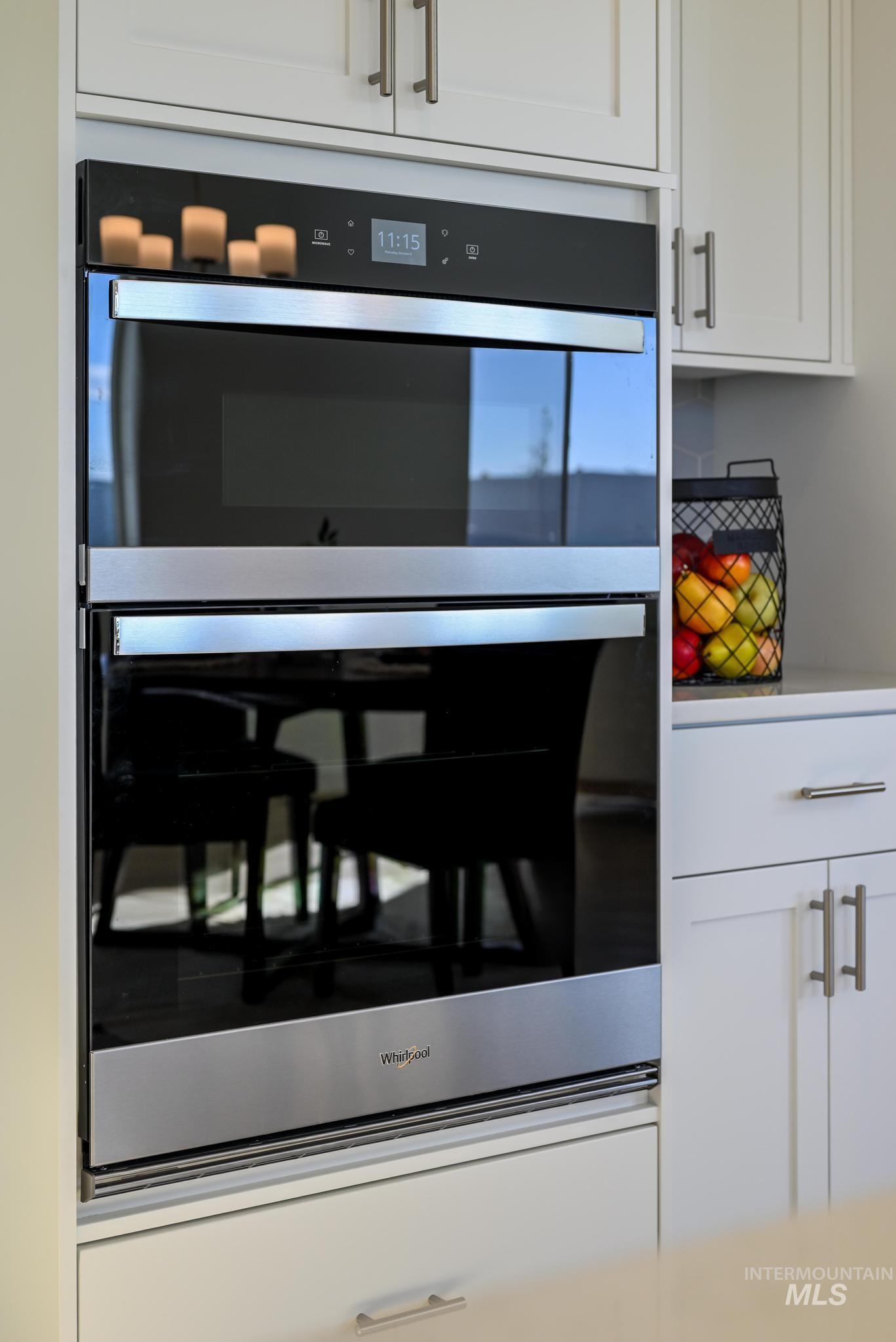 Kitchen view of white cabinetry, double oven, and light countertops