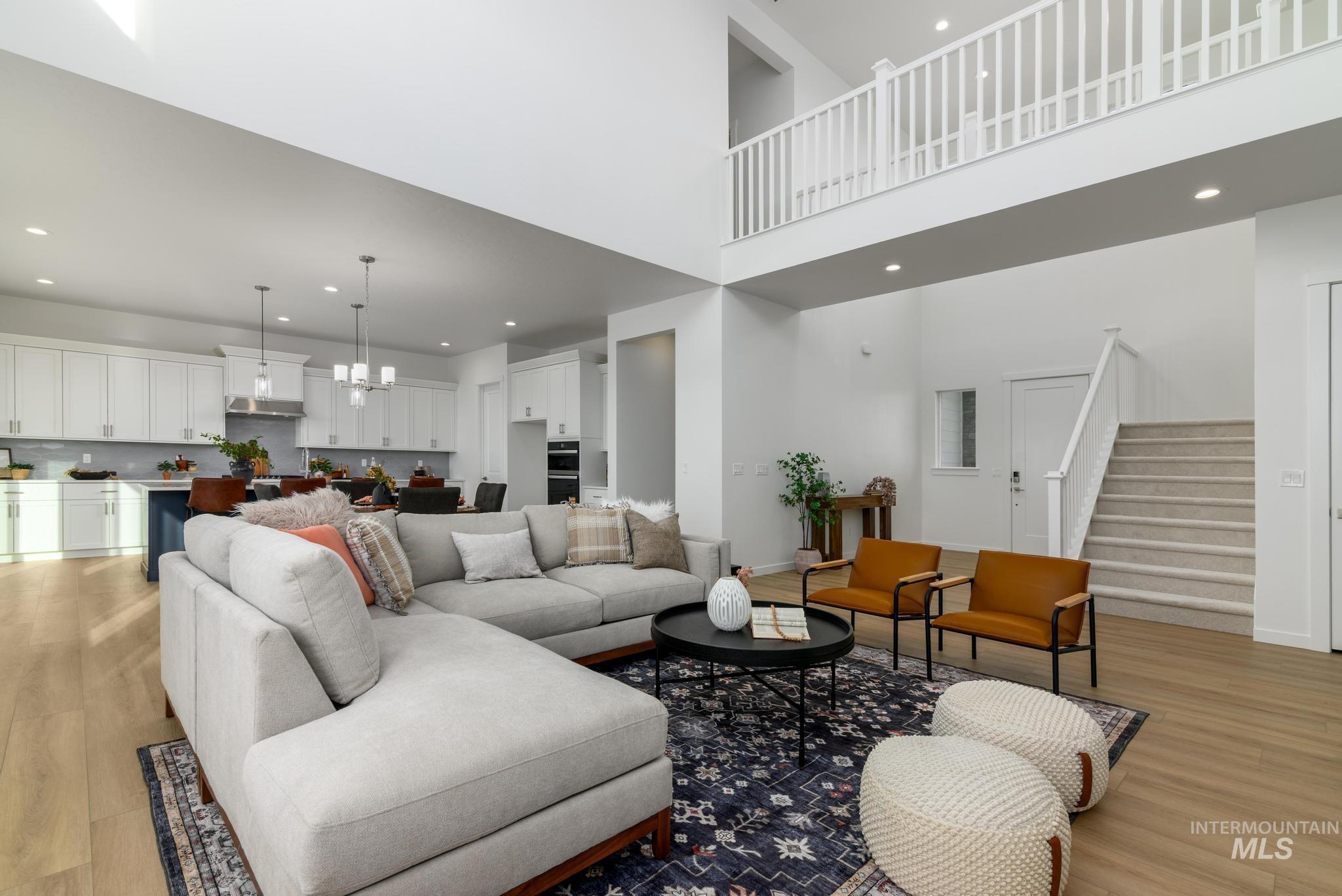 Living area featuring stairway, light wood-style flooring, recessed lighting, a chandelier, and a towering ceiling
