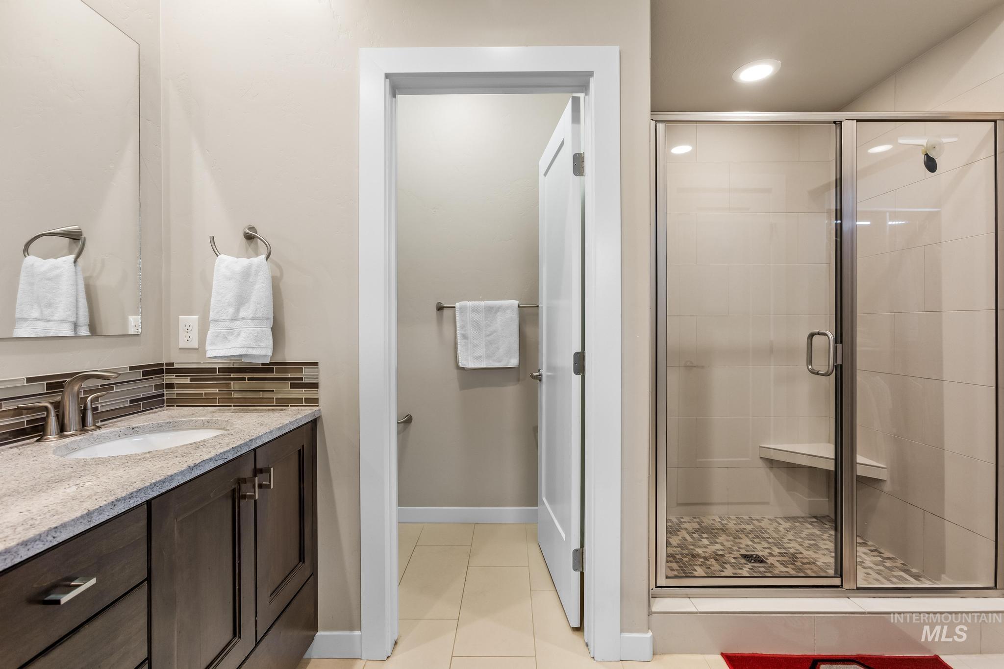 Bathroom with vanity, a shower stall, light tile patterned floors, backsplash, and recessed lighting