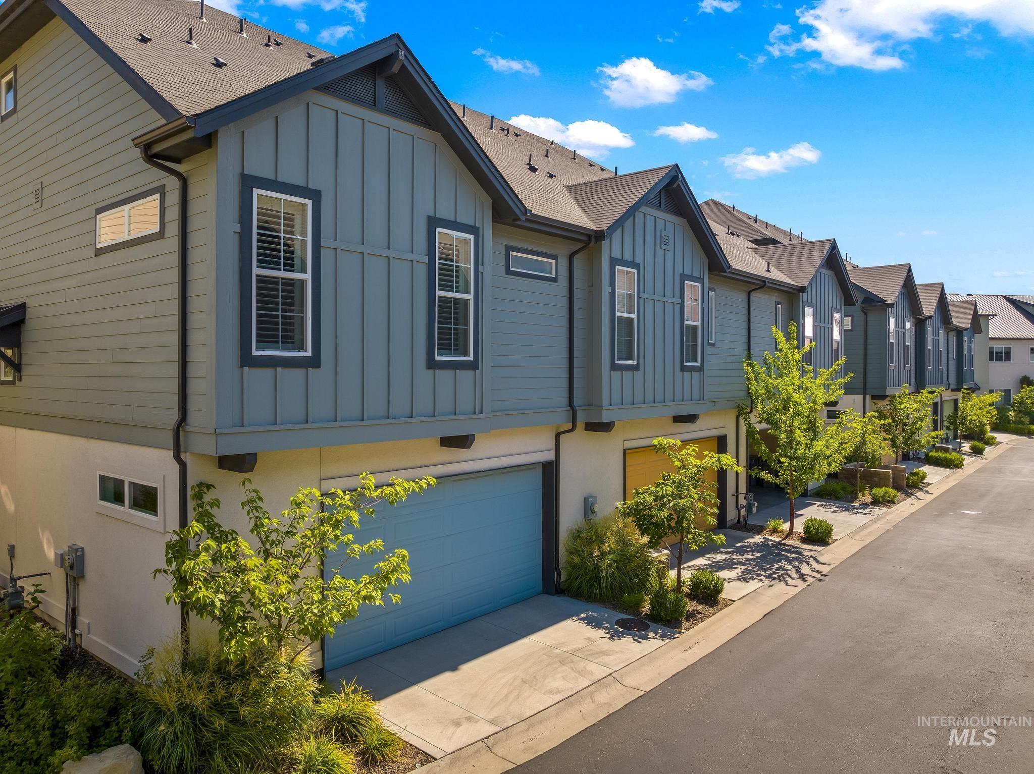 View of home's exterior featuring board and batten siding, a residential view, an attached garage, driveway, and a shingled roof