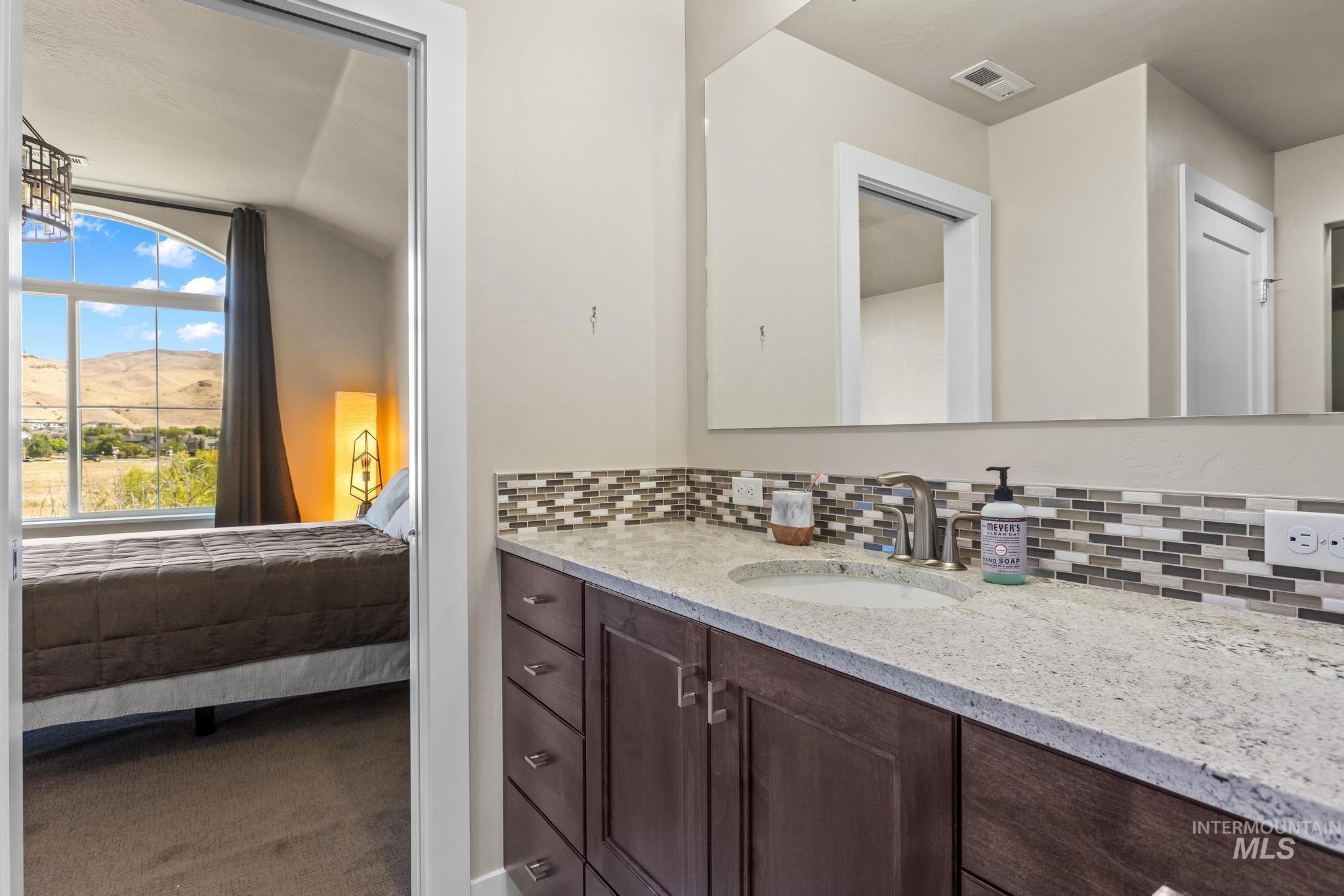 Ensuite bathroom featuring vanity, backsplash, and a mountain view