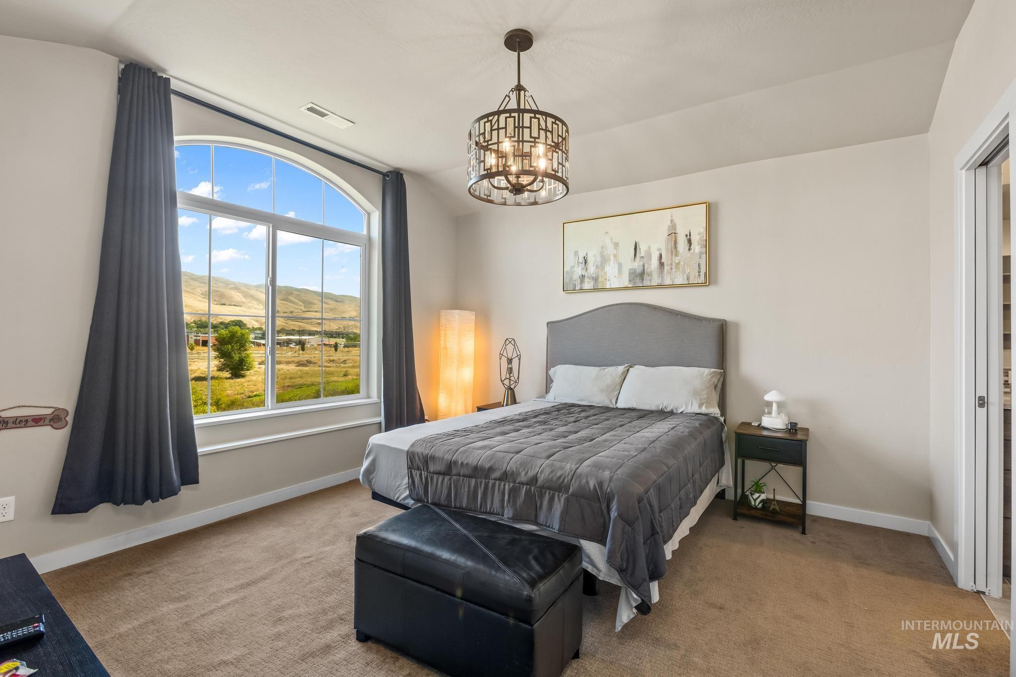 Carpeted bedroom with a mountain view, a chandelier, and vaulted ceiling