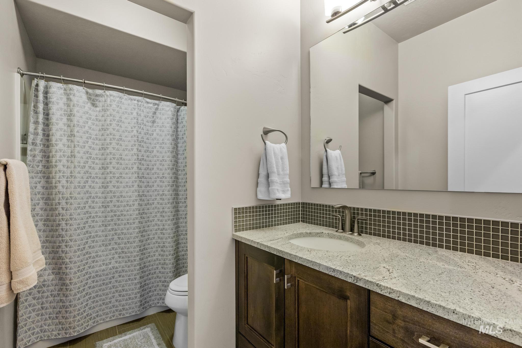 Full bath with vanity, tasteful backsplash, and a shower with shower curtain