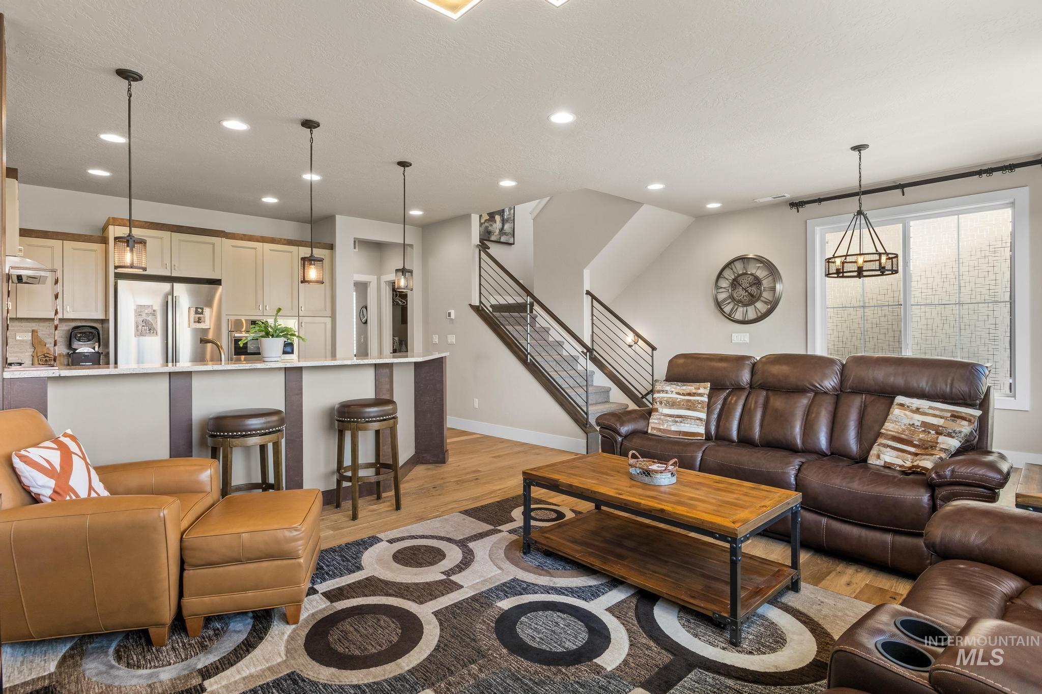 Living area featuring stairs, light wood-type flooring, recessed lighting, and a chandelier