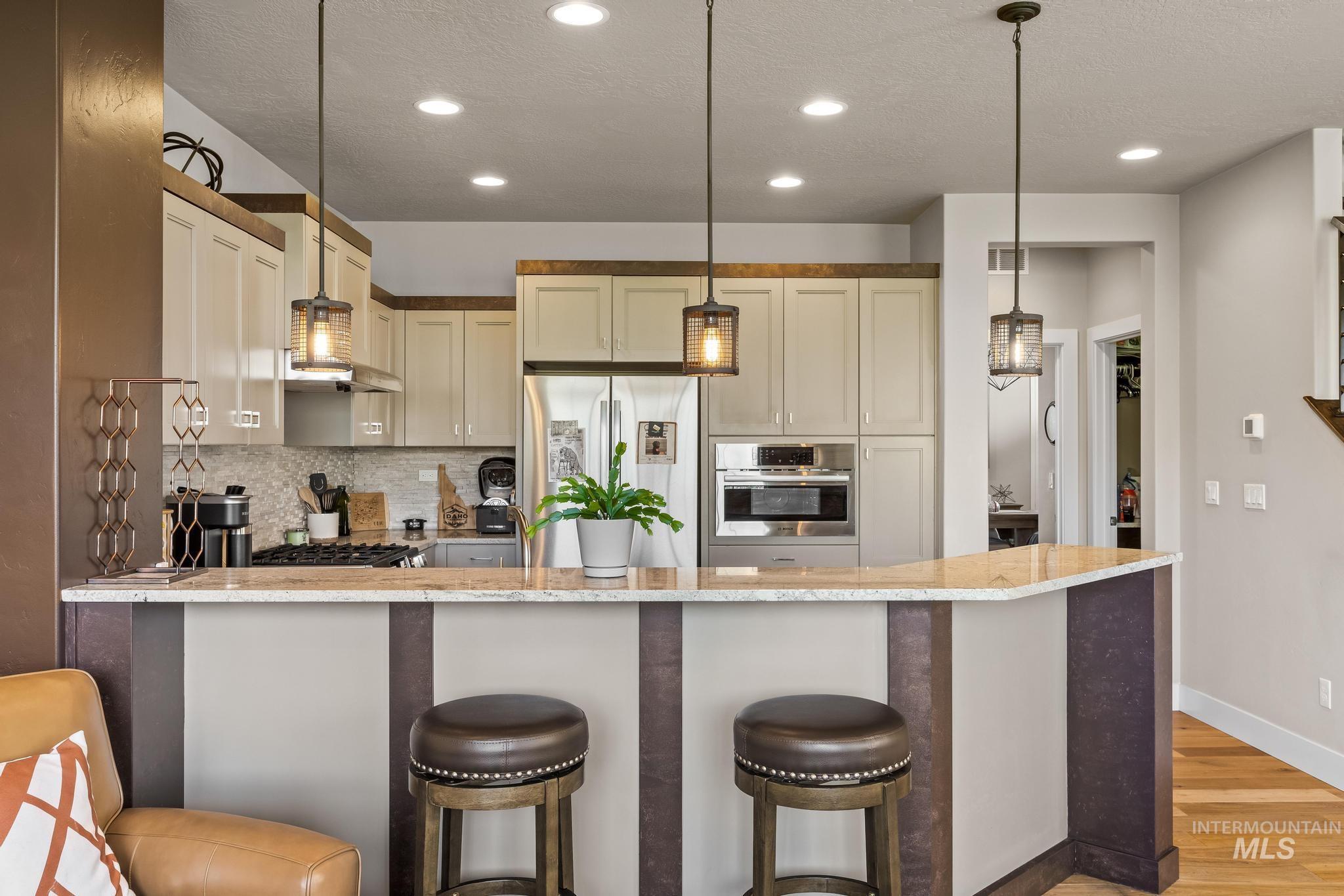 Kitchen with a peninsula, tasteful backsplash, light stone countertops, stainless steel appliances, and a textured ceiling