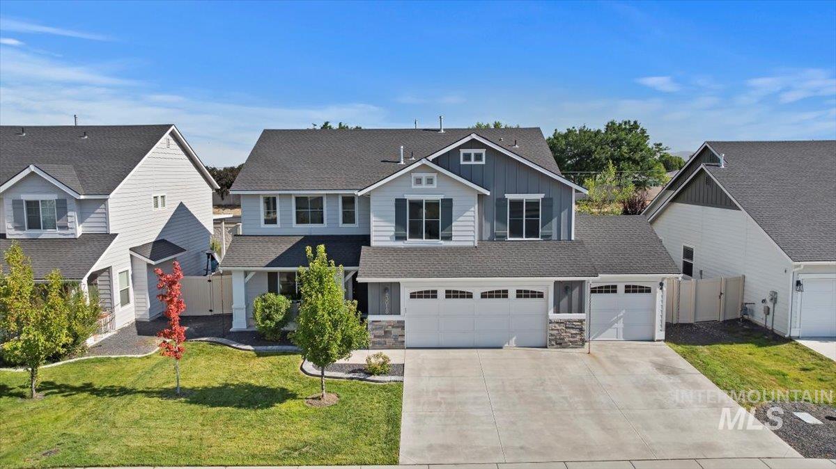 View of front facade featuring concrete driveway, stone siding, board and batten siding, roof with shingles, and an attached garage